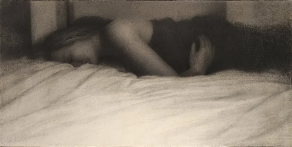 A woman sleeping on her side on a bed, with her head resting on a pillow.