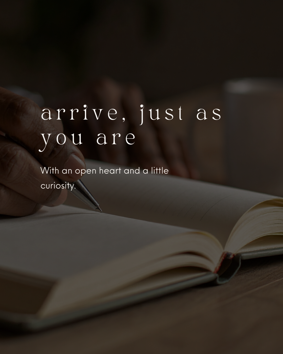 Close-up of a person's hand writing in a notebook with a pen, with a motivational quote overlayed that says, "arrive, just as you are. With an open heart and a little curiosity."