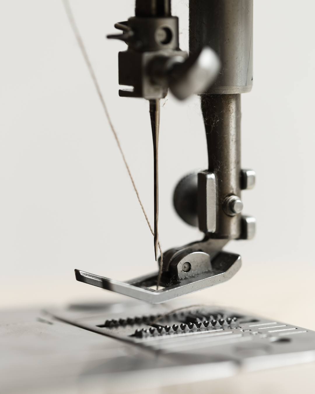 Punta di un ago di una macchina da cucire in metallo che si trova sopra il tessuto.