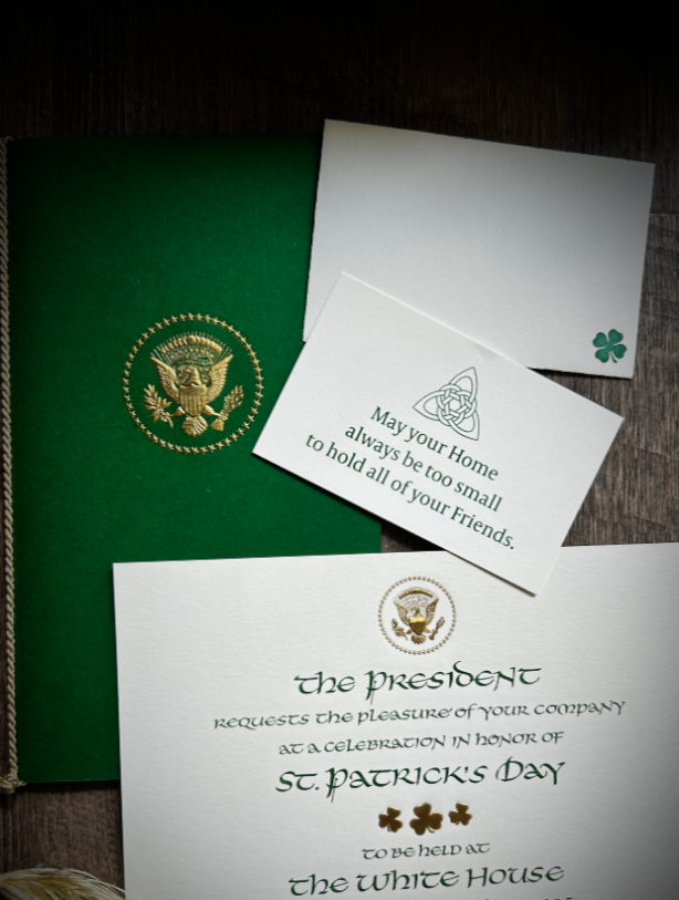 Presidential St. Patrick's Day invitation letter and small cards with presidential seal, lucky symbols, placed on a wooden surface.