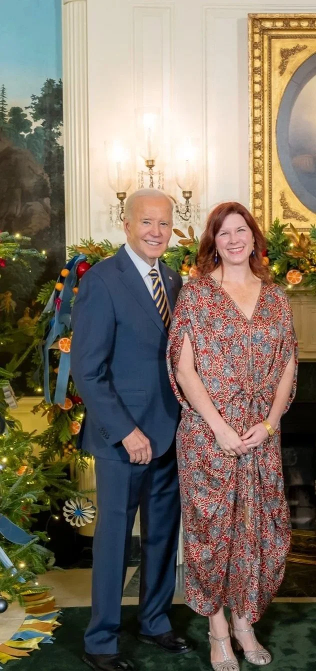 Professional photo of Moira Jamrisko and President Joe Biden. It establishes Moira's authority as a former State Department diplomatic gifts officer, highlighting the origins of Grand Unveiling’s strategic and historically-grounded approach
