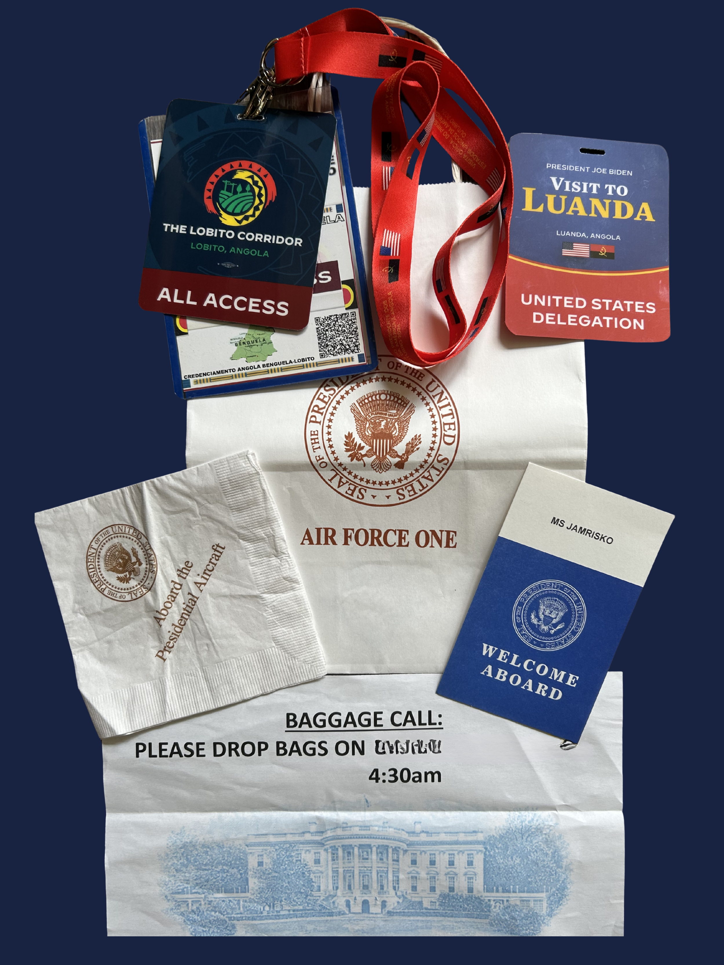 A flat lay of diplomatic travel artifacts for Moira Jamrisko: Air Force One napkins, 'Welcome Aboard' cards, and United States Delegation badges for President Biden’s visit to Luanda, Angola, and the Lobito Corridor. Proof of high-level protocol.