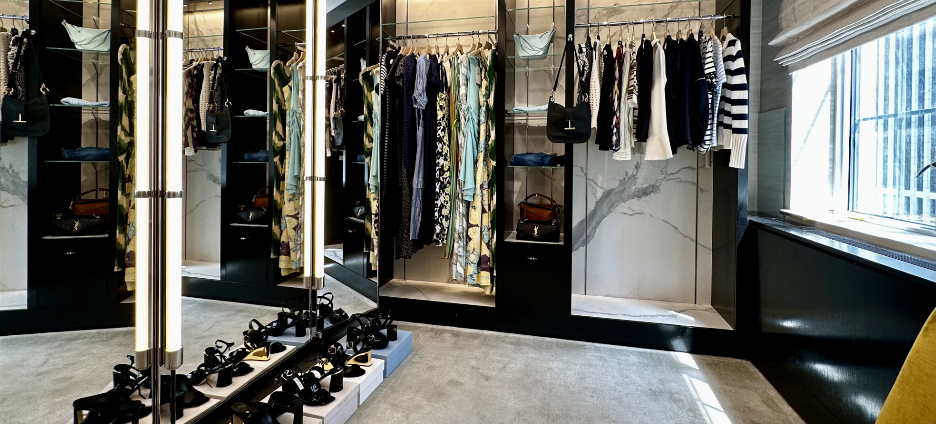 Clothing racks with dresses and tops, shelves with handbags, and a shoe display in a boutique store.