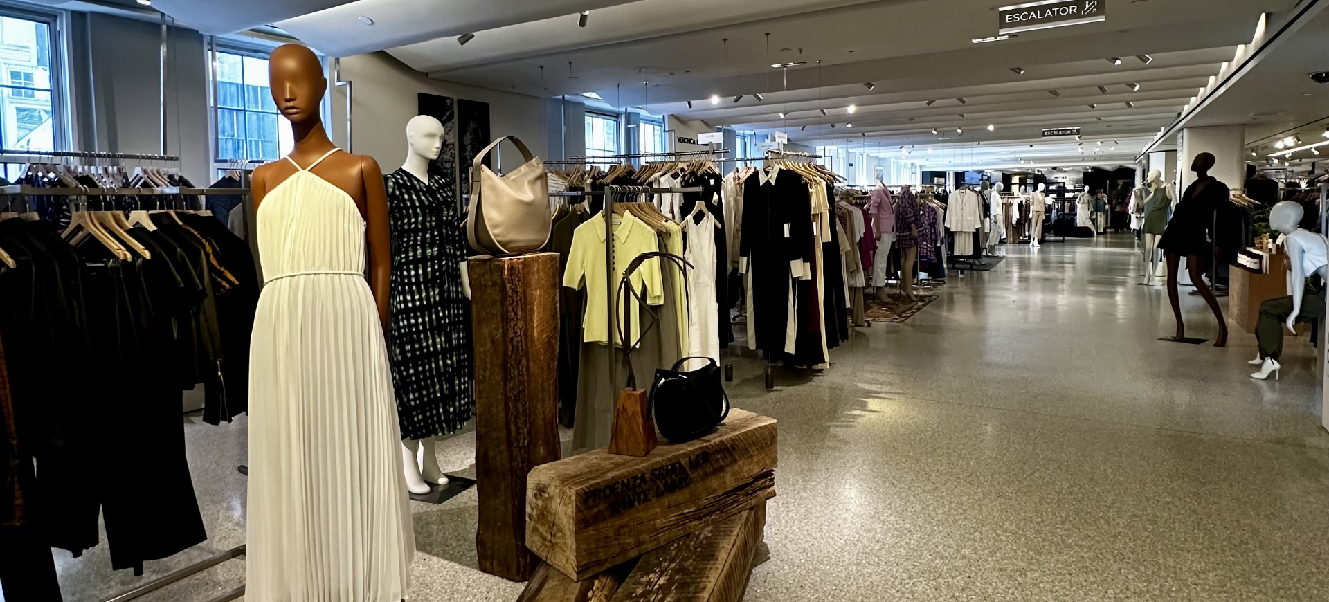 Interior of a clothing store with mannequins displaying dresses and various clothing racks filled with apparel.