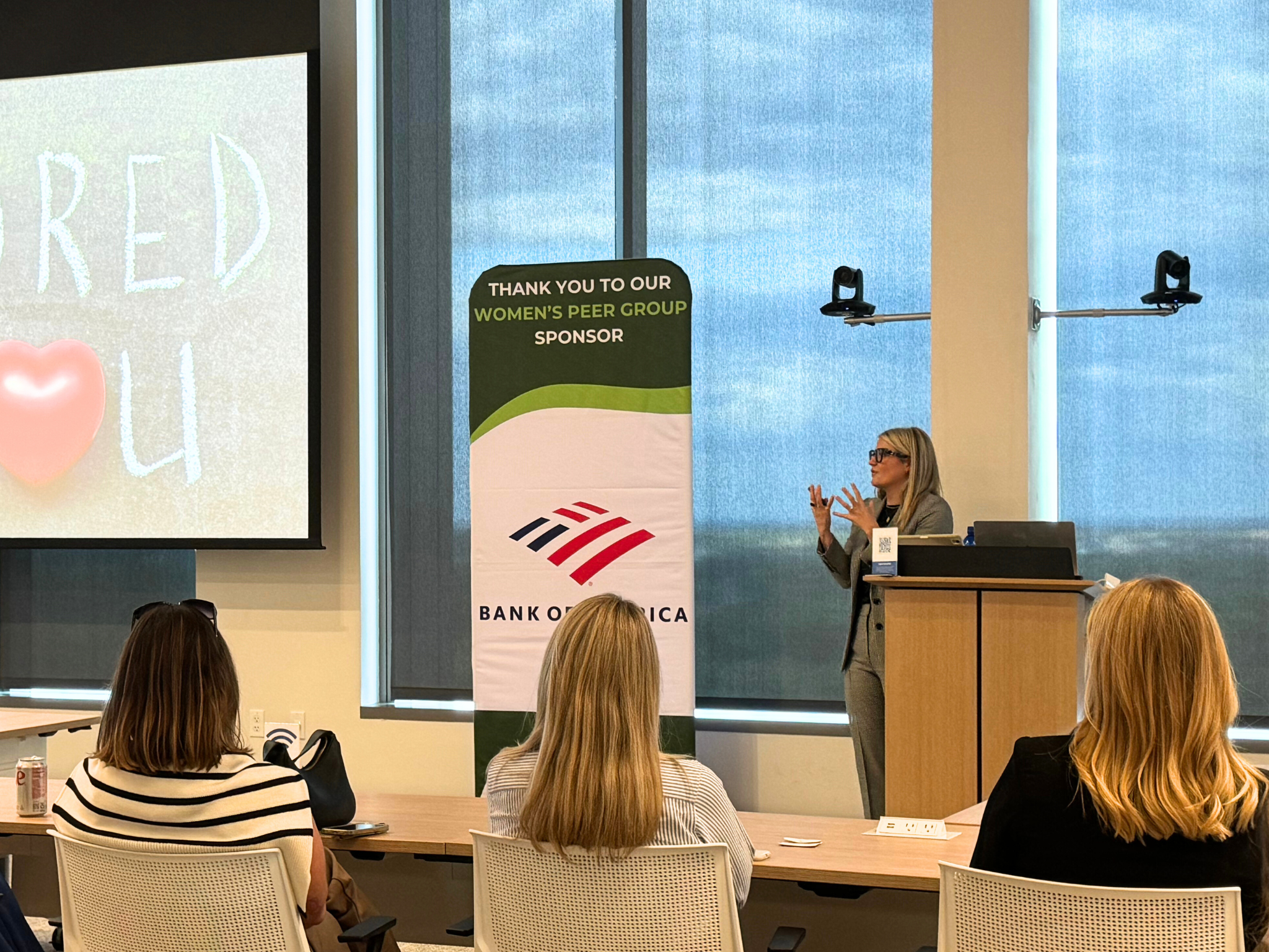 Laura K. Sawyier is giving a presentation in a conference room, with a large screen on the left.