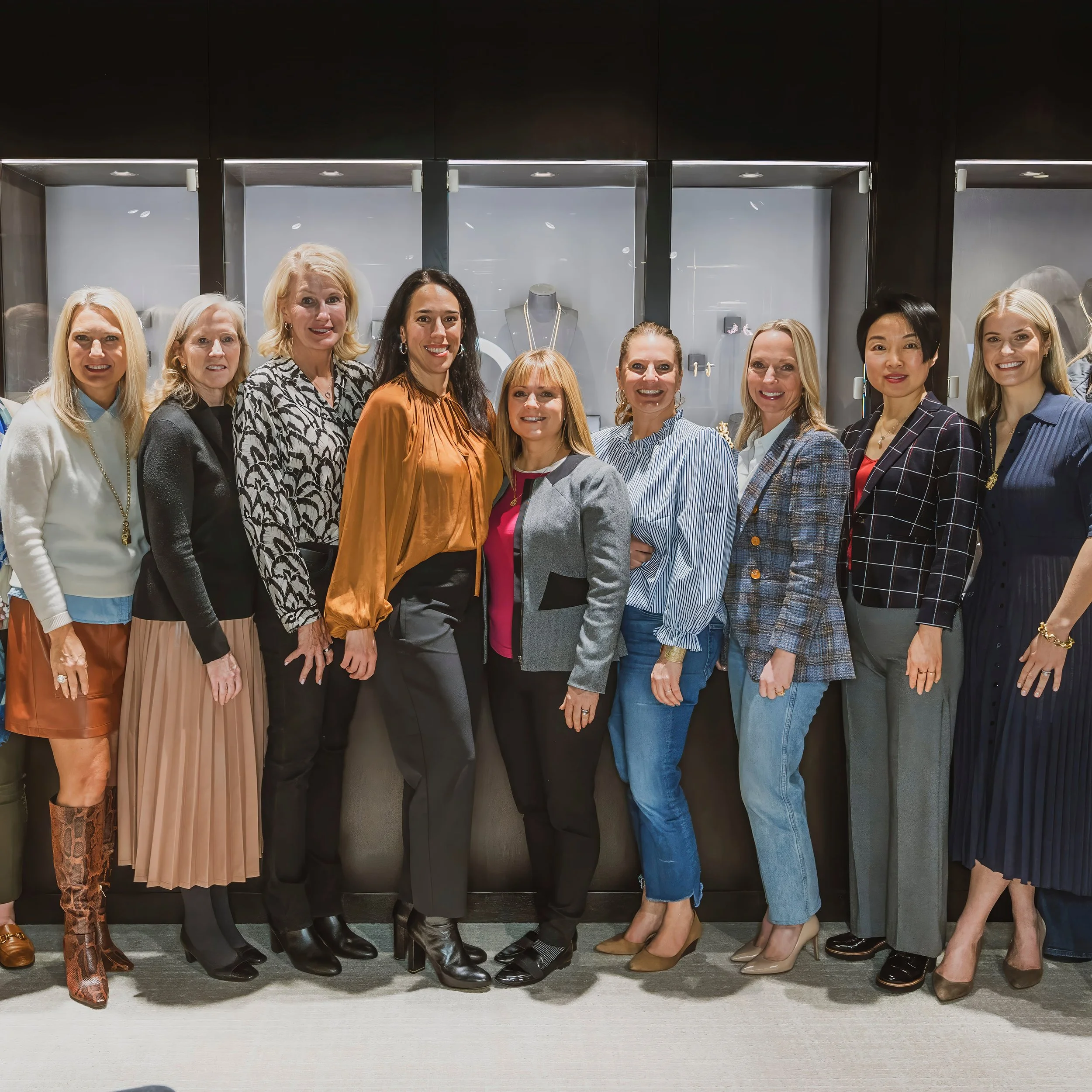 Group of ten women standing inside a jewelry store, smiling for the camera.
