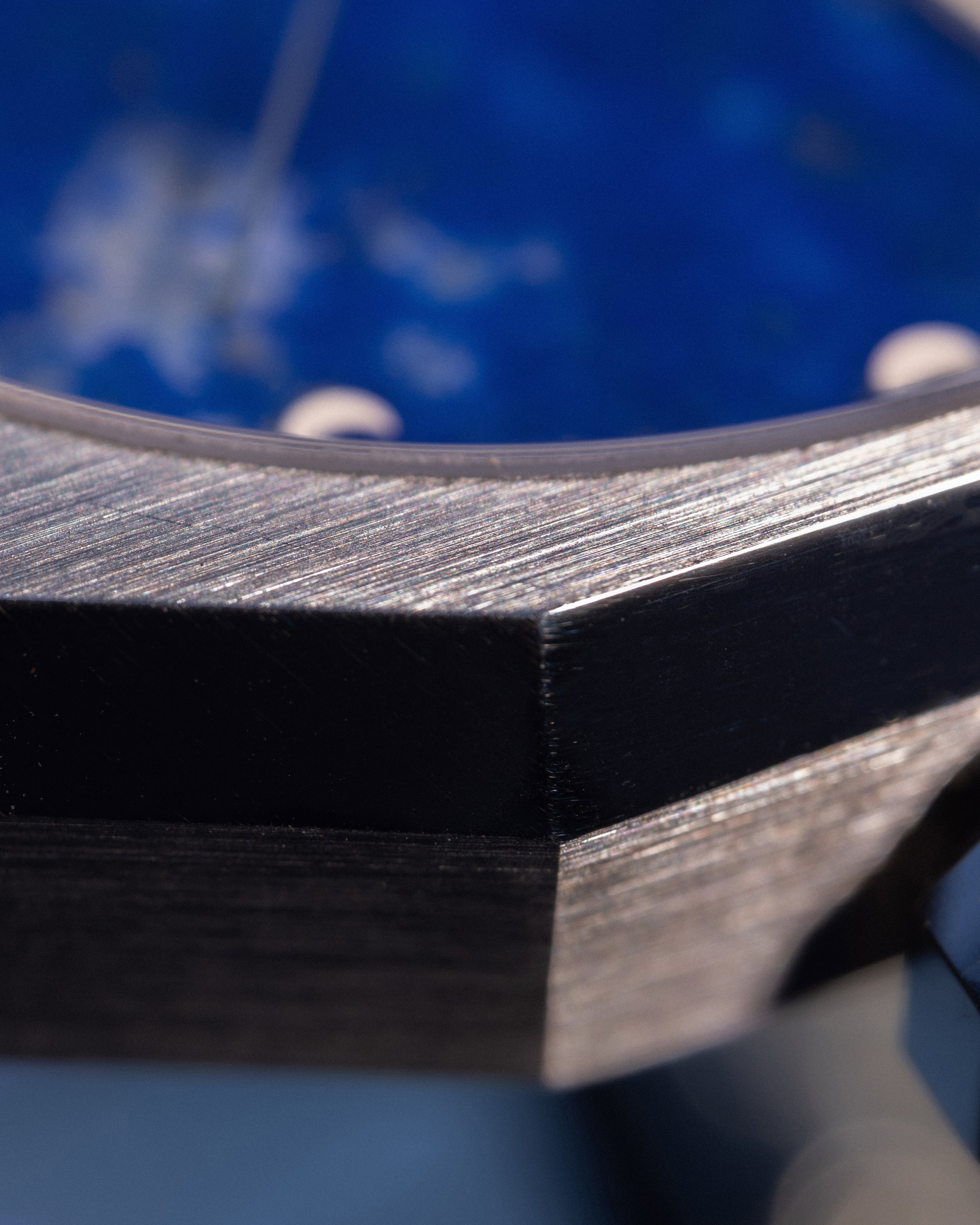 Nahaufnahme eines Uhrengehäuses, im Hintergrund ist das blaue Zifferblatt mit mondphasigen Indizes zu erkennen. 