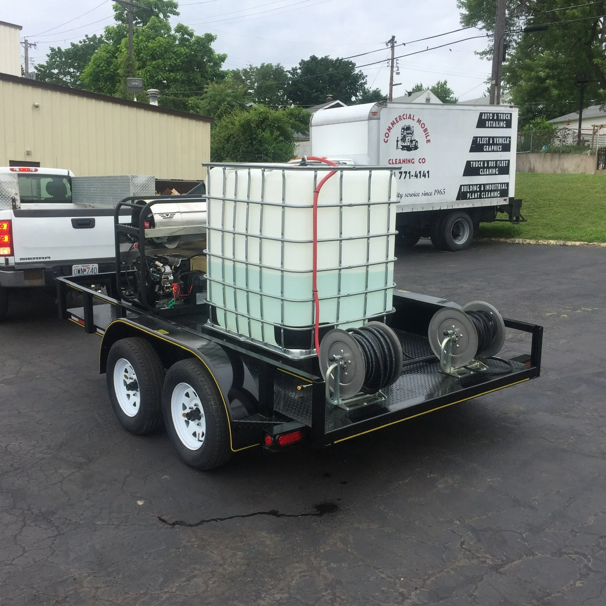 Mobile power washing trailer with water tank and hose reels.