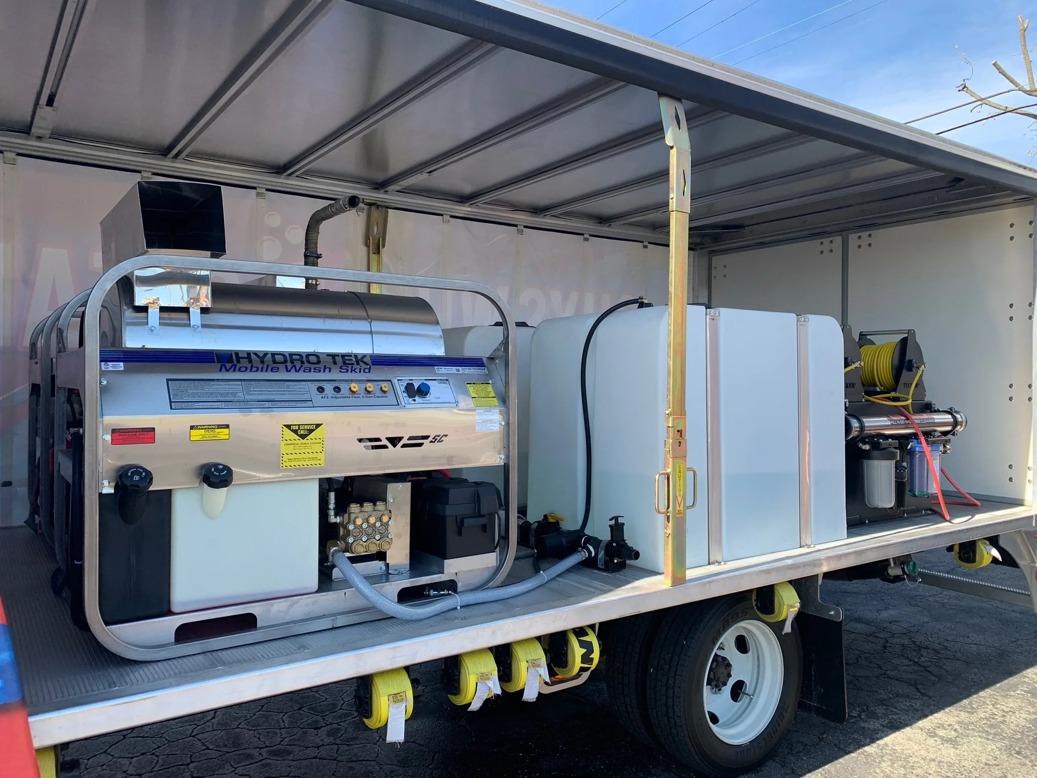 Mobile wash skid equipment inside a truck, featuring Hydro Tek cleaning system with tanks and hoses.