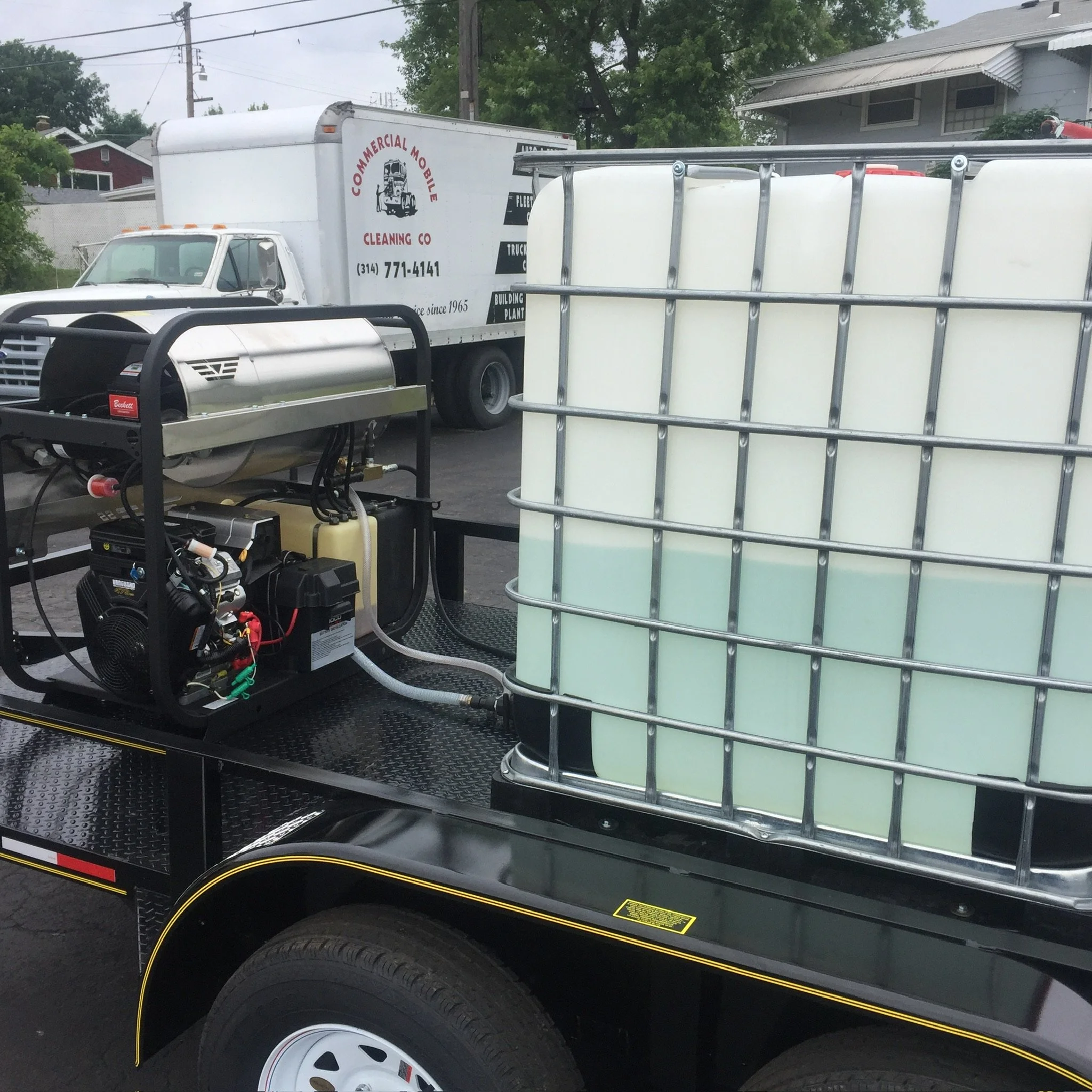 Trailer with a large water tank and pressure washer on a cleaning service truck.