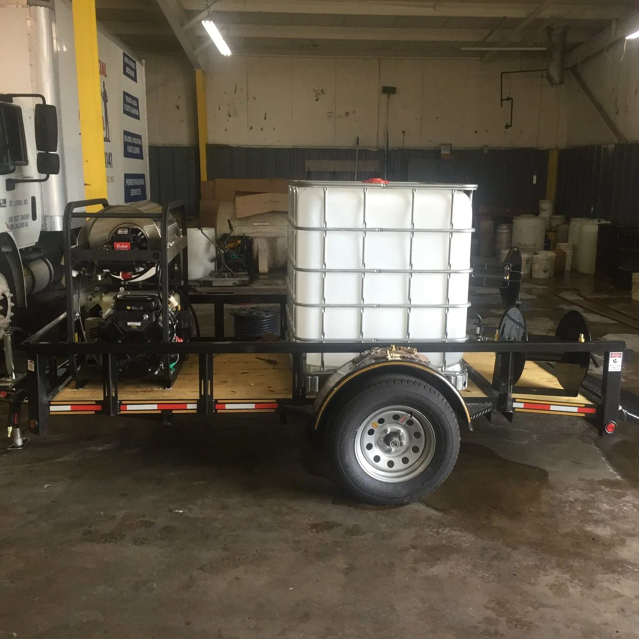 Trailer with a large water tank and equipment in a garage.