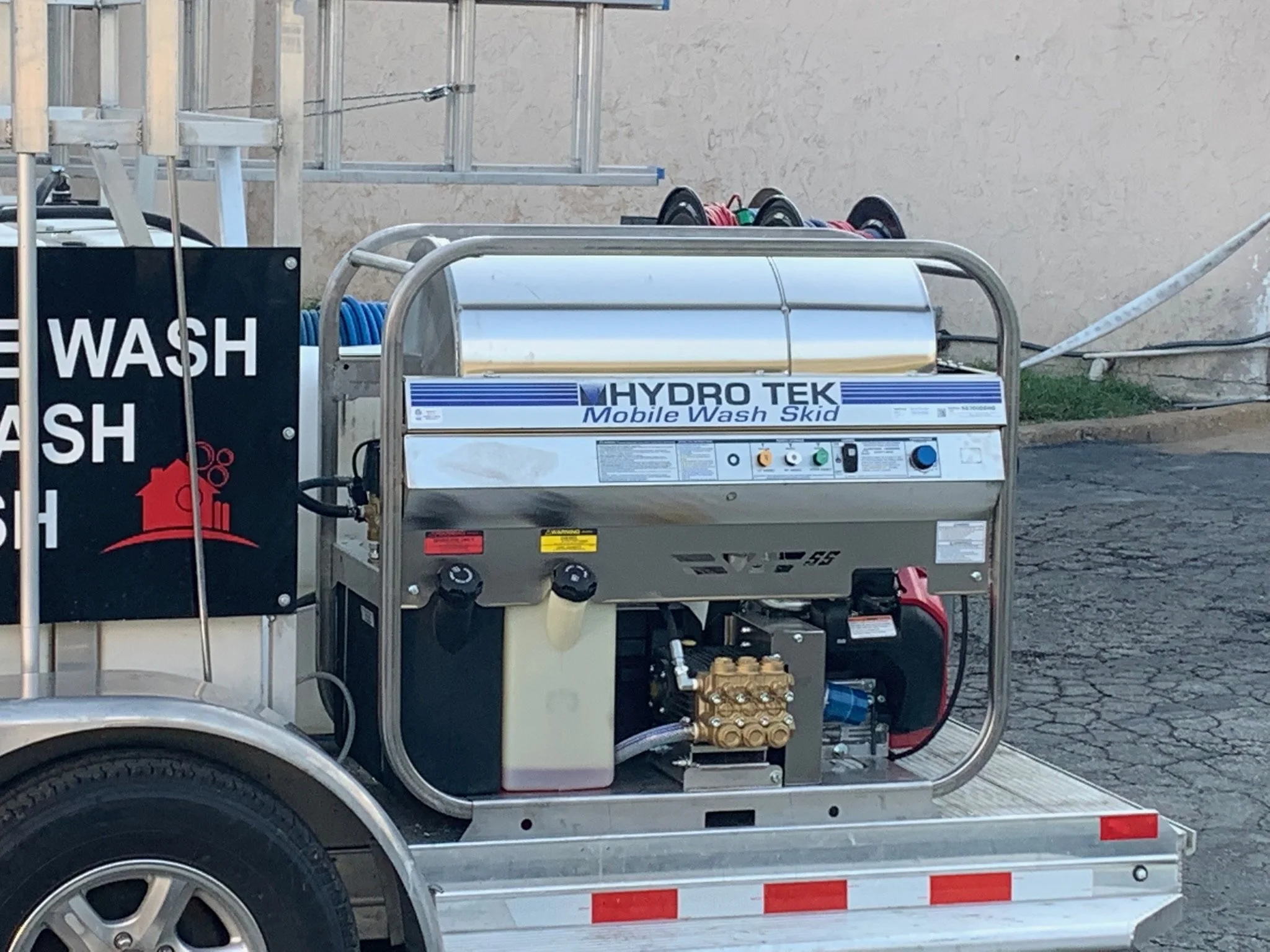 A Hydro Tek mobile wash skid mounted on a trailer, used for pressure washing, with visible hoses and control panel.