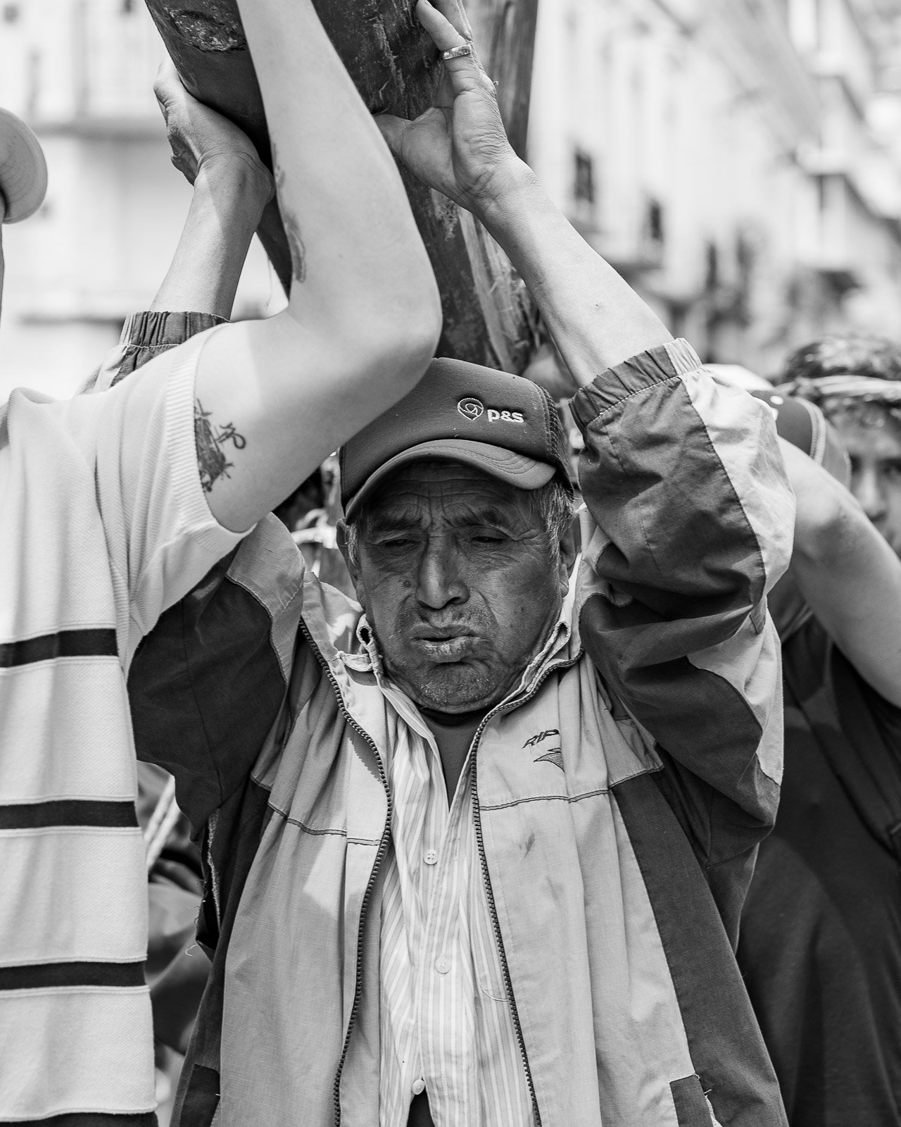 Hombre cargando un objeto en una calle concurrida en una fotografía en blanco y negro.