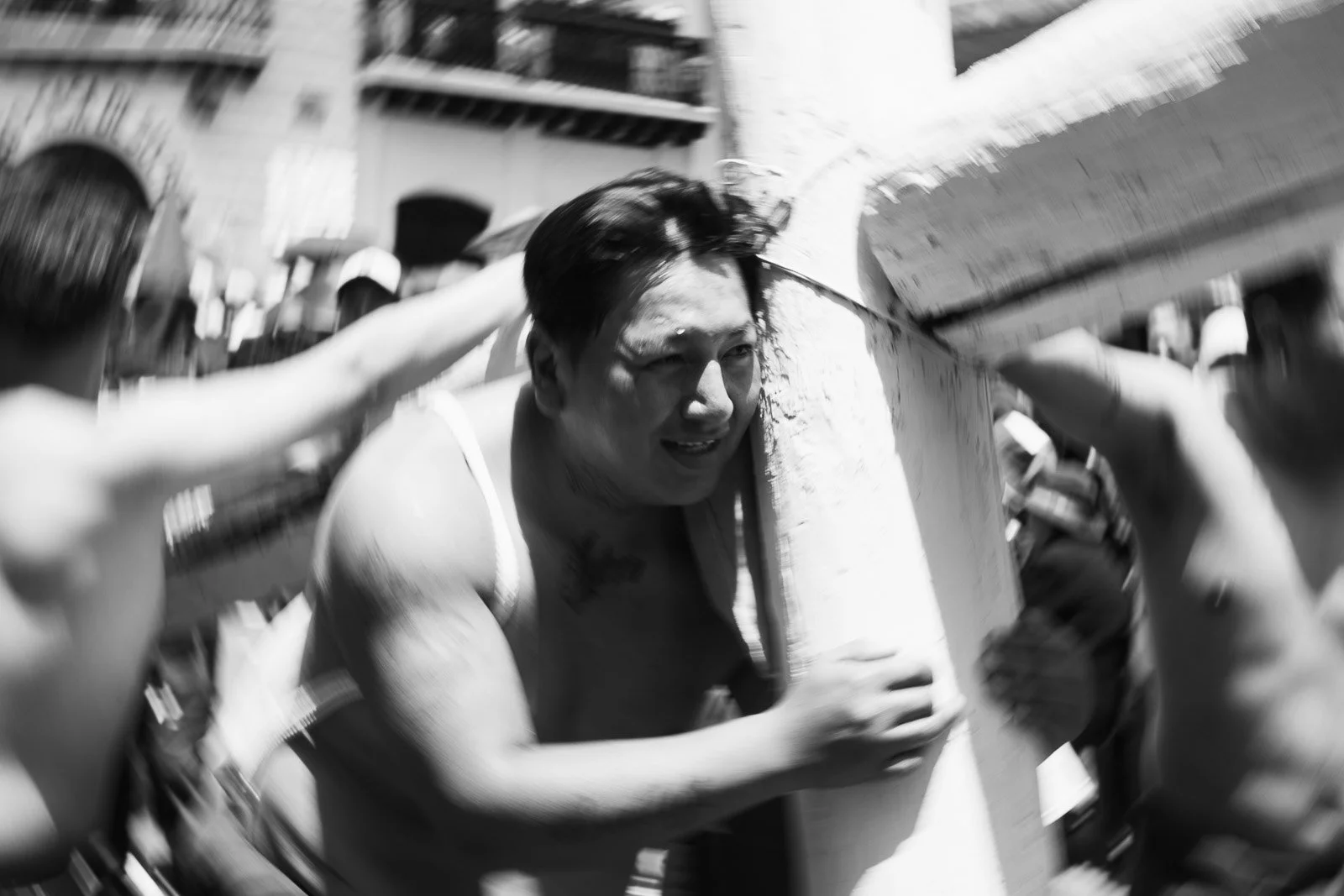 Un hombre participando en una fiesta tradicional, cargando un objeto en la cabeza mientras rodeado de personas.