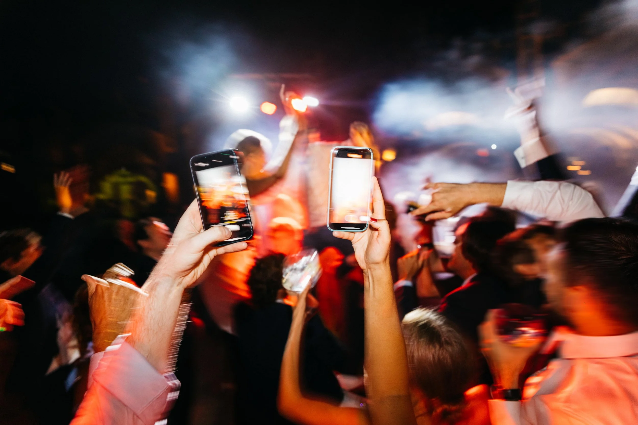 Dos manos sosteniendo teléfonos en una fiesta