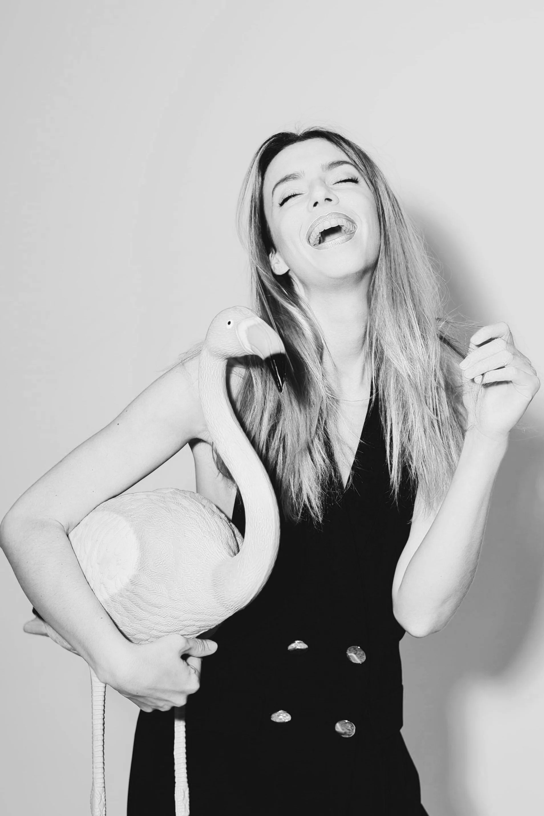 Mujer divertida que sostiene un flamenco de peluche en una celebración de Año Nuevo.