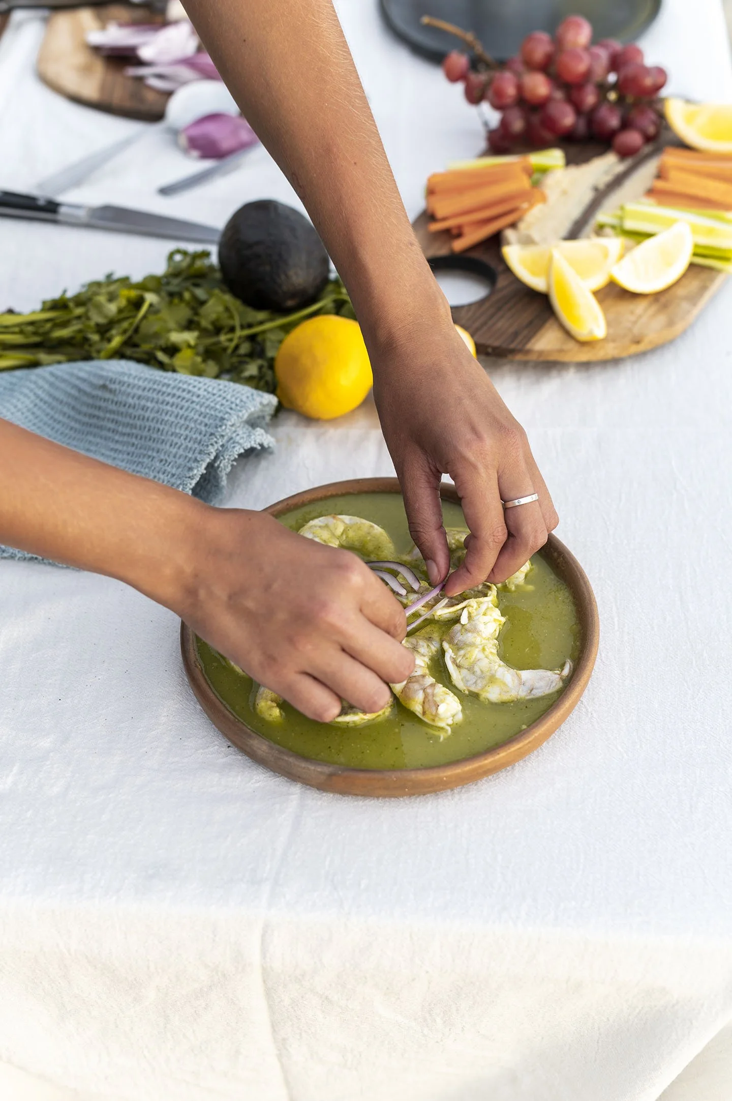 Dos manos emplatando mariscos con una guarnición