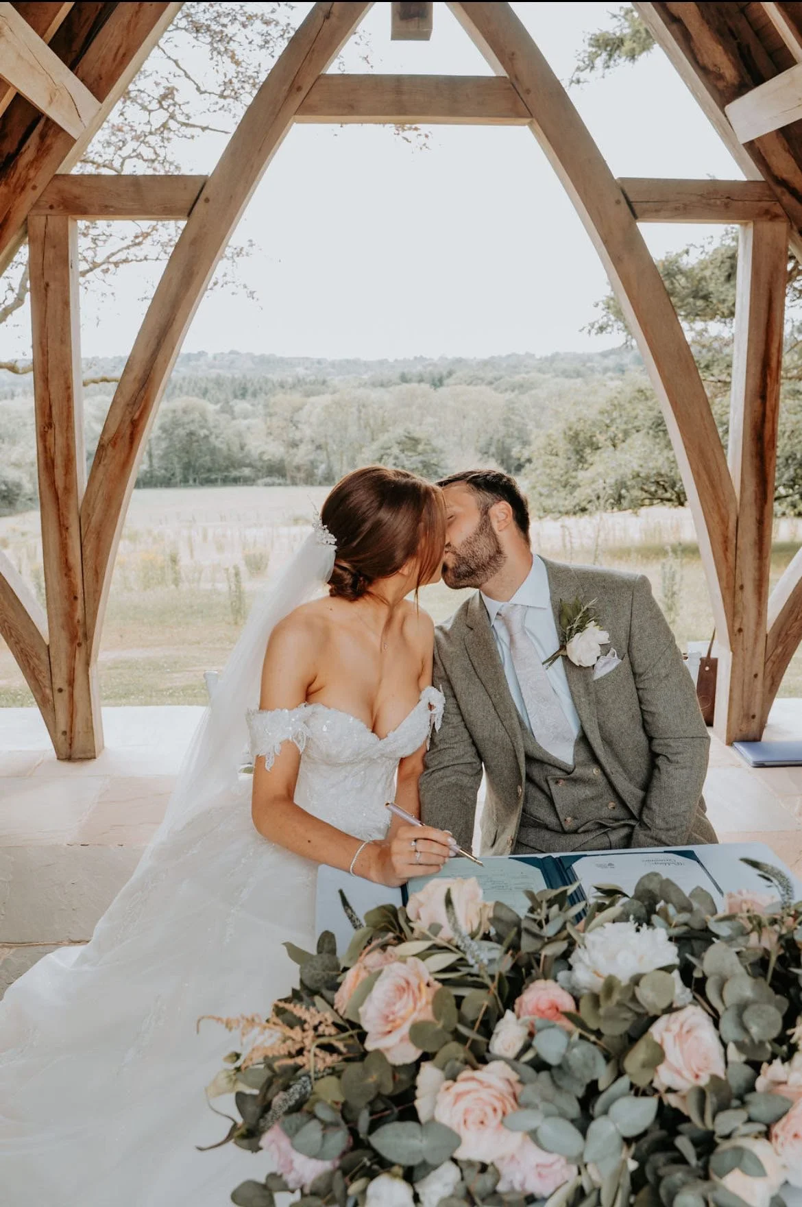 Bride and Groom with signing table arrangement of Eucalyptus and peach roses