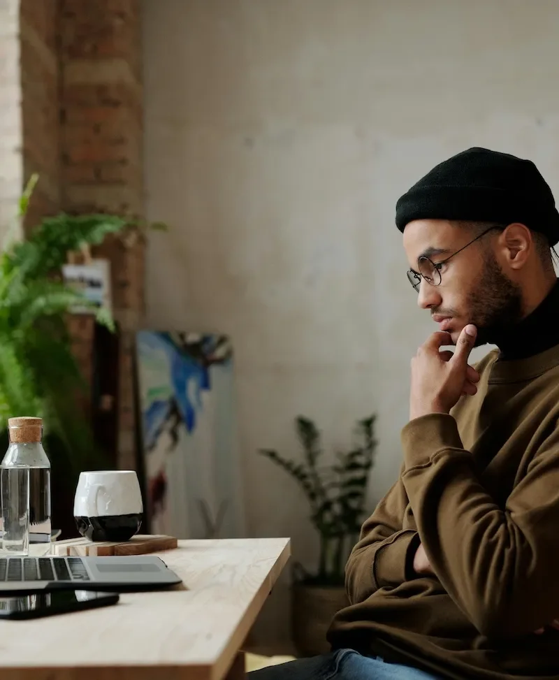 man sitting at desk looking at laptop