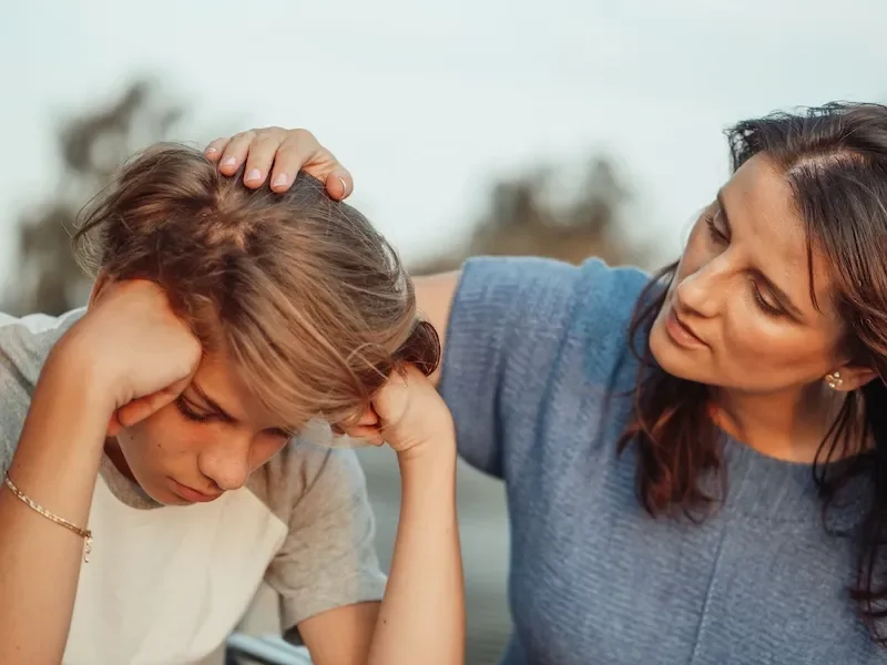 mother talking to teenage son comforting him