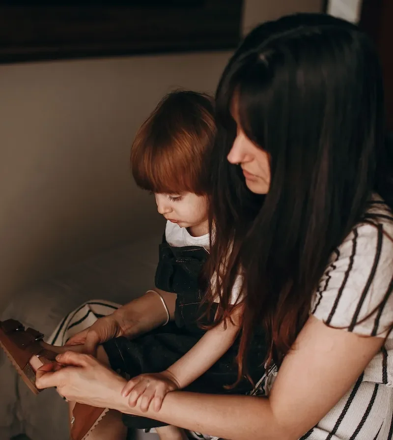 mother helping daughter put on shoes