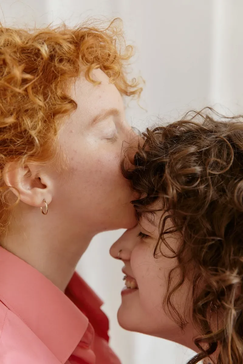 woman kissing partner on forehead