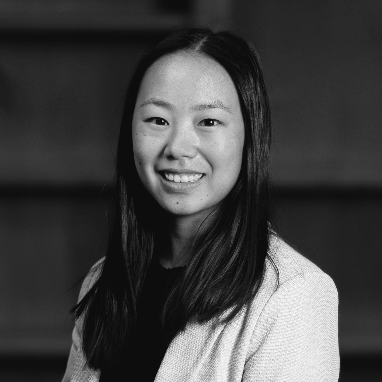 Black and white portrait of a young woman with long dark hair smiling at the camera.