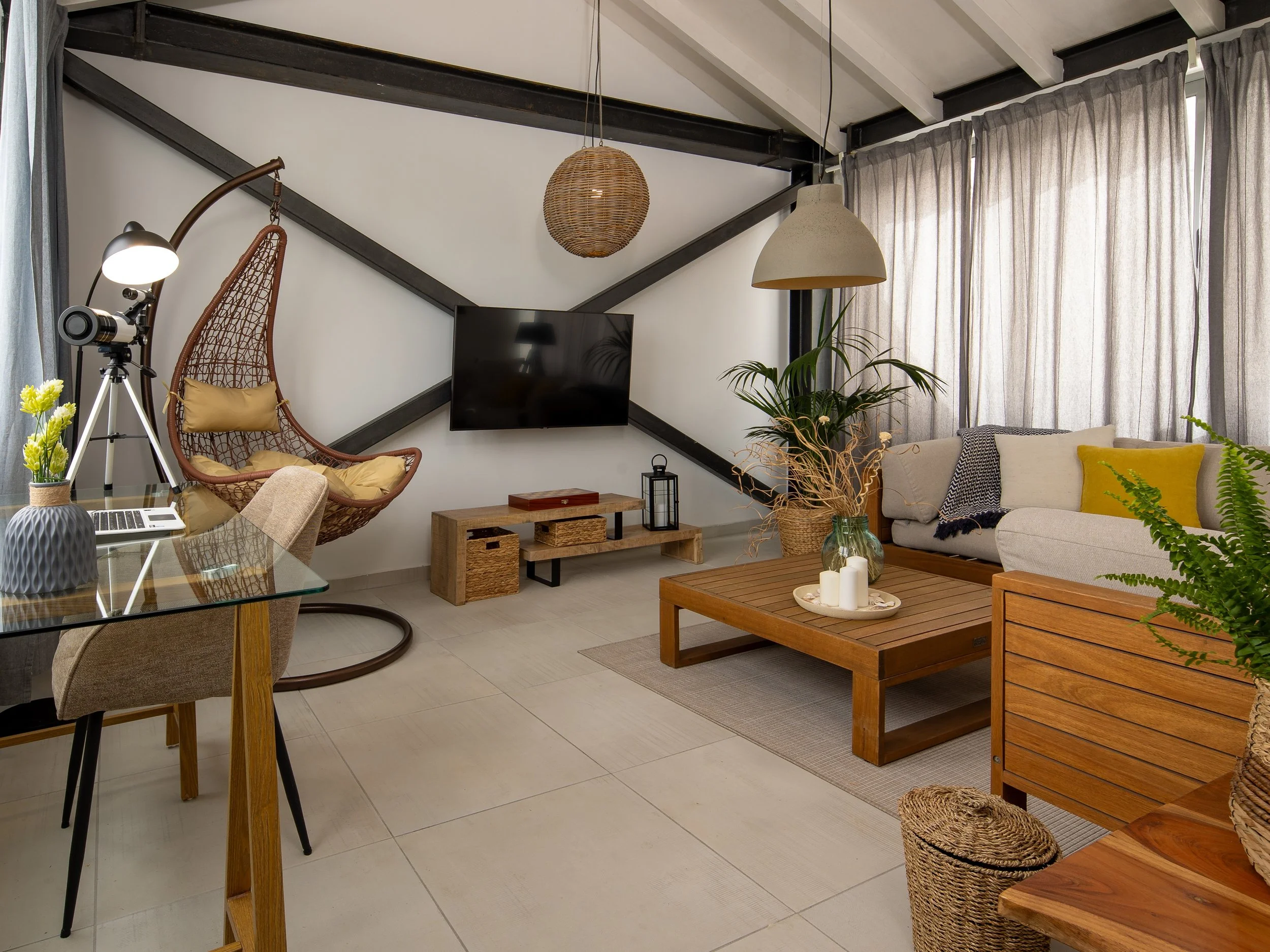 Bright living room with an amazing sea view, featuring a large sofa, TV, a stylish hanging chair, and a desk.