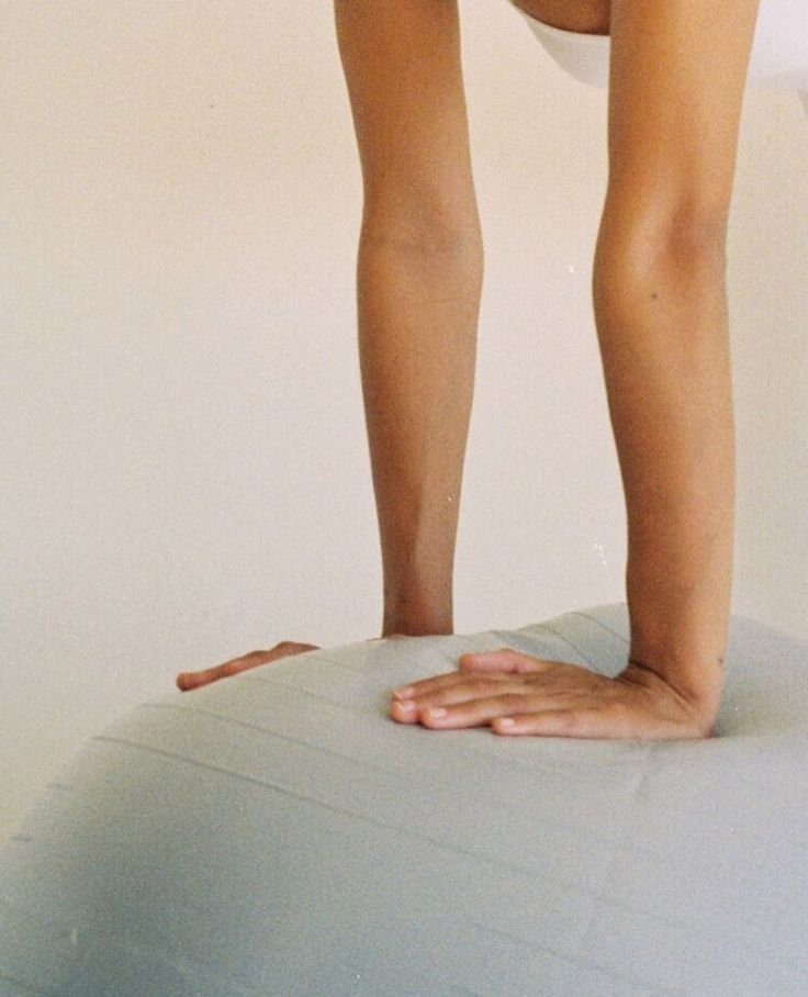 Person performng a yoga pose on a mat with arms extended and hands on the mat, body positioned vertically in a plank pose.