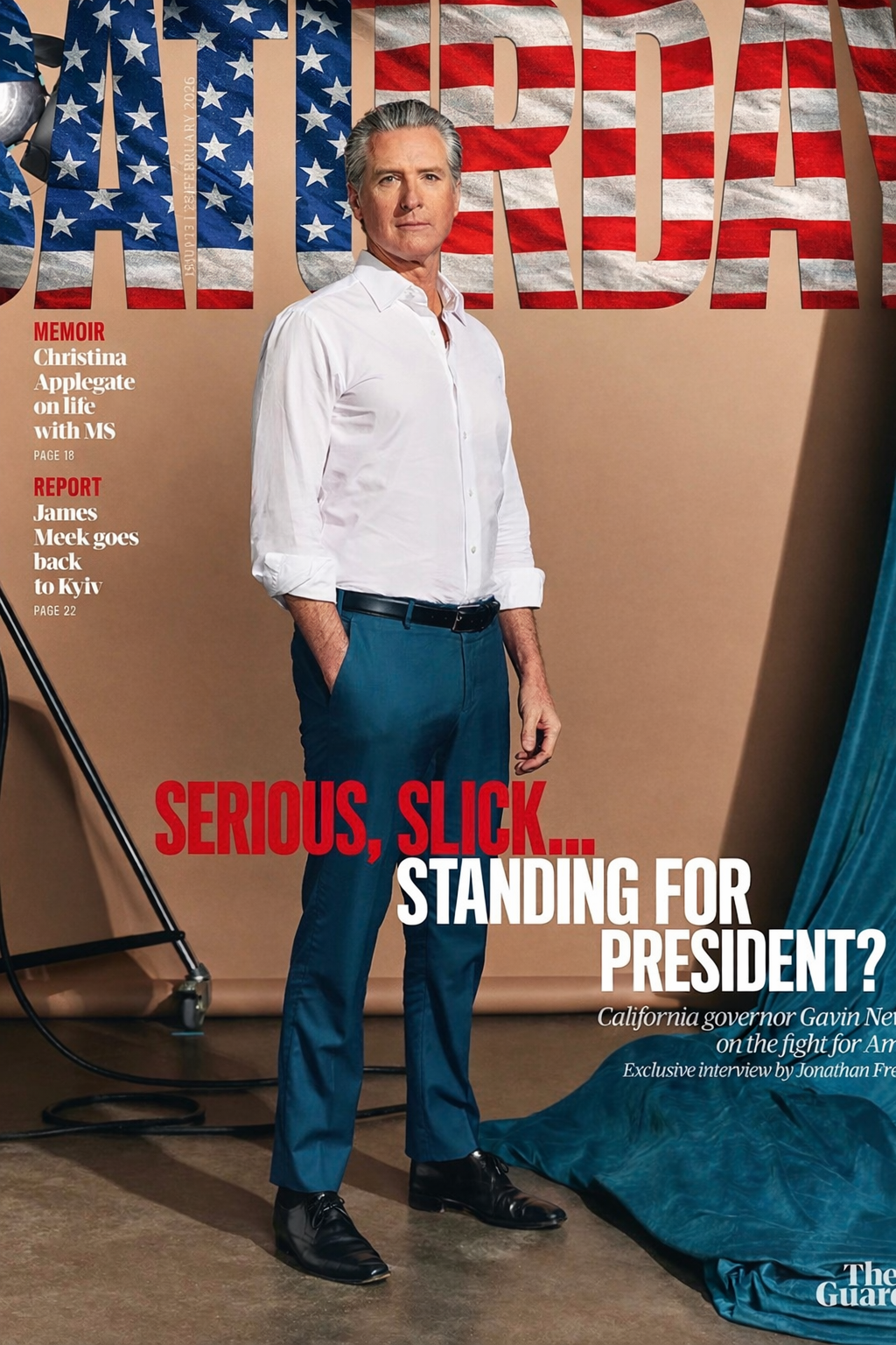 Gavin Newsom dressed in a white shirt and blue pants, standing sideways with his hands in his pockets, in front of a backdrop with large American flag-style letters spelling 'AMERICA'.