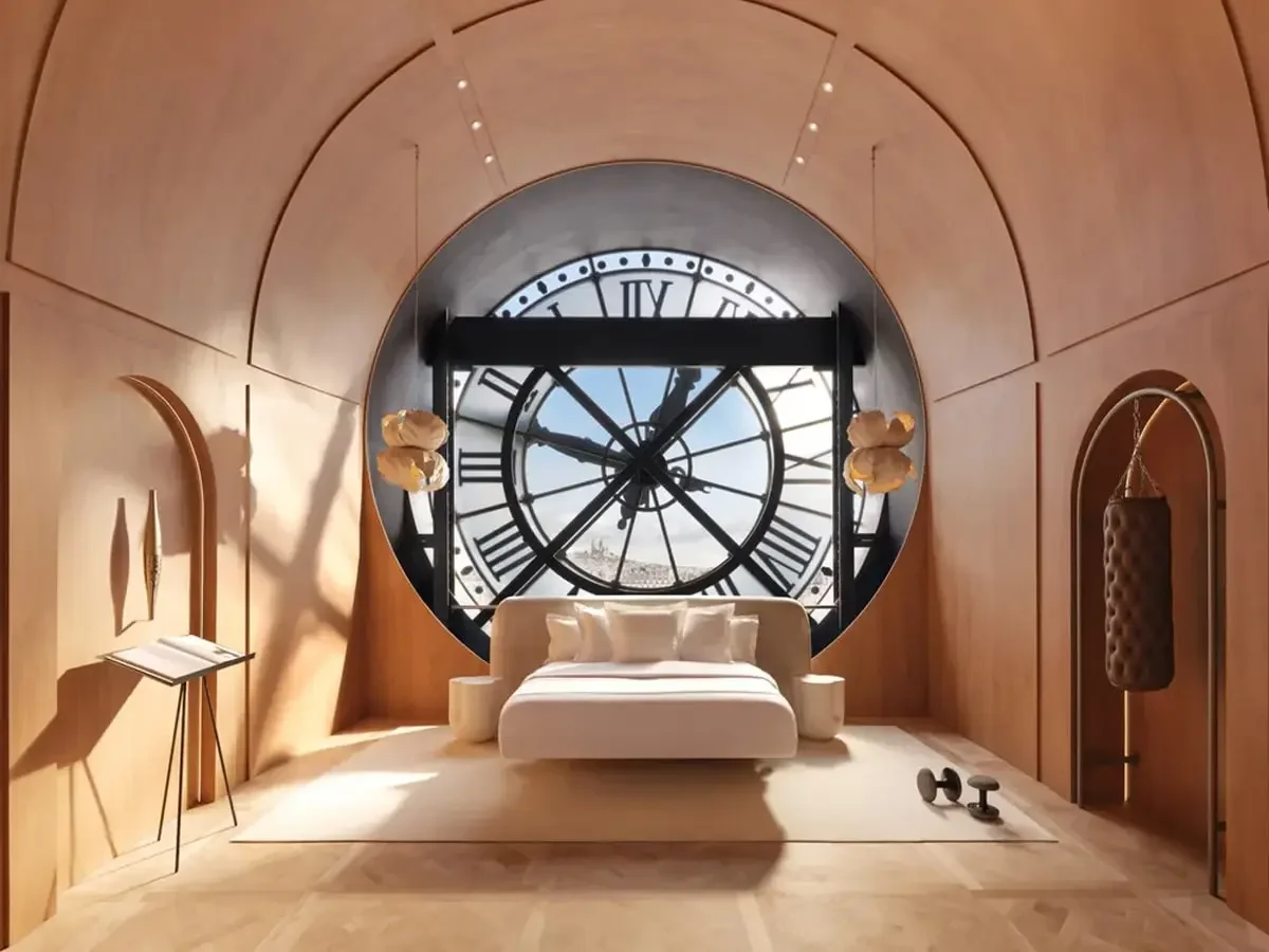 A bedroom with a large round window resembling a clock face, featuring Roman numerals, and a view of blue sky. The room has wooden walls and ceiling, a white bed with pillows, two side tables, ornate wall lamps, a small desk with a book, and a pair of dumbbells on the floor.