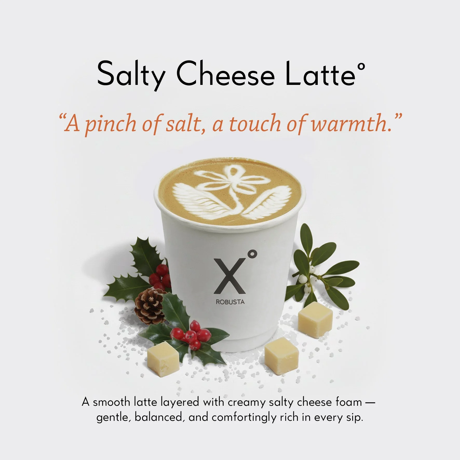 Salty Cheese Latte by X° Robusta, topped with latte art and surrounded by holiday decorations.