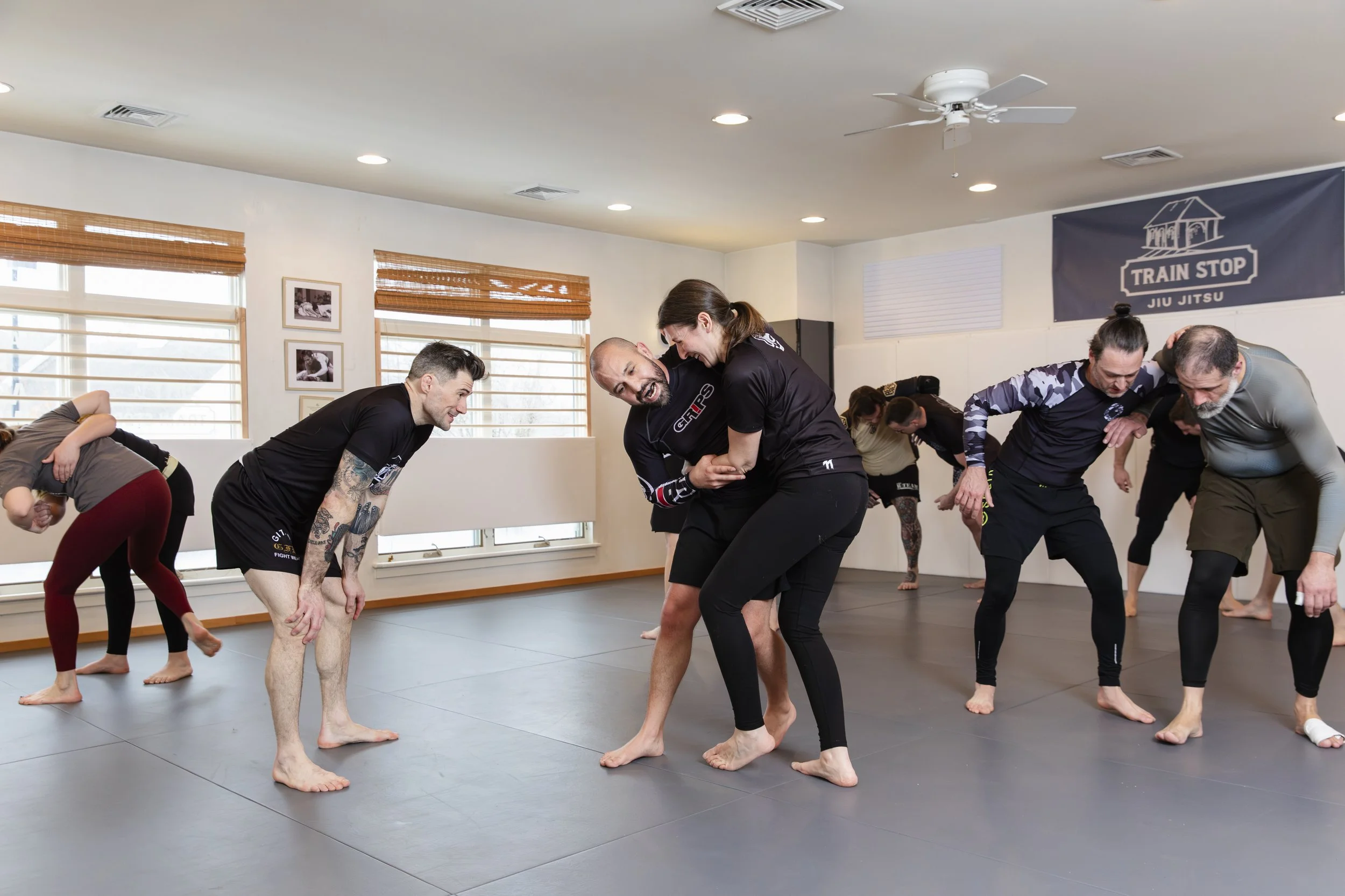 People practicing Brazilian Jiu Jitsu in a martial arts gym.