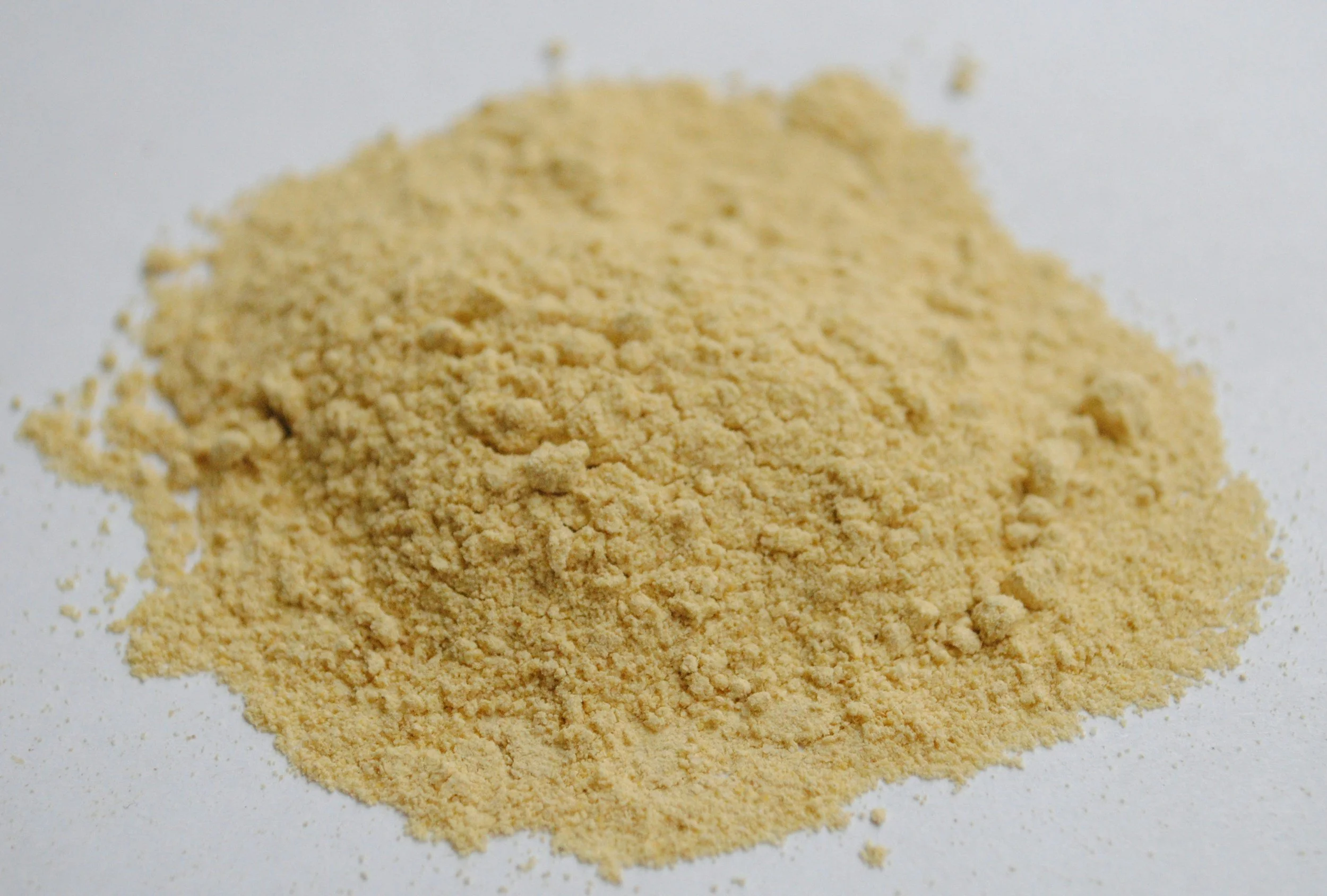 Close-up of a pile of beige powder on a white surface.