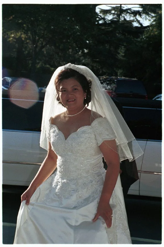 Bride in white wedding dress and veil outdoors.