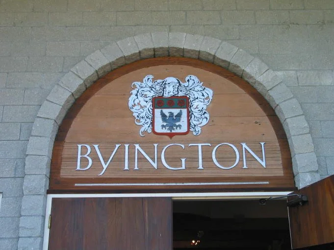 Arched sign with the word "BYINGTON" and a decorative coat of arms above an entrance.