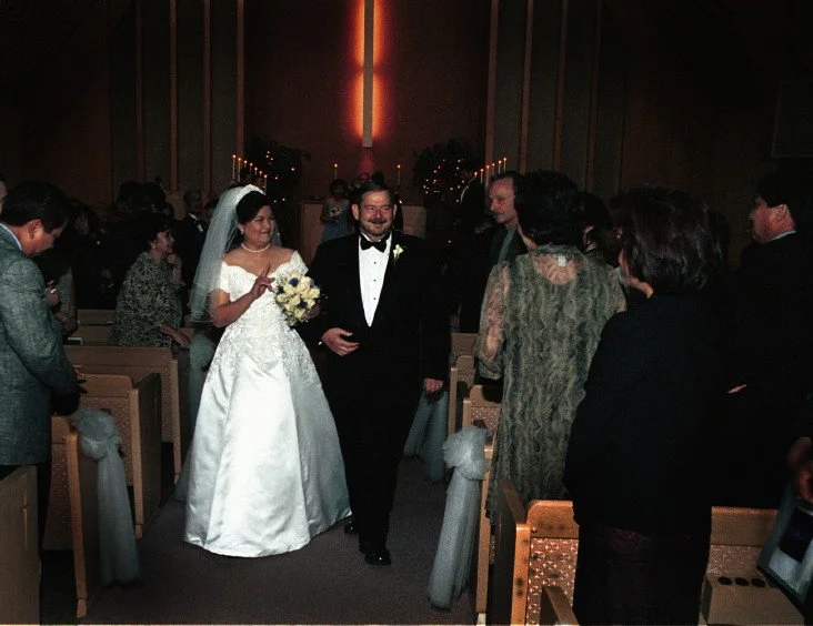 Bride and groom walking down the aisle at a wedding ceremony, surrounded by guests in a church.