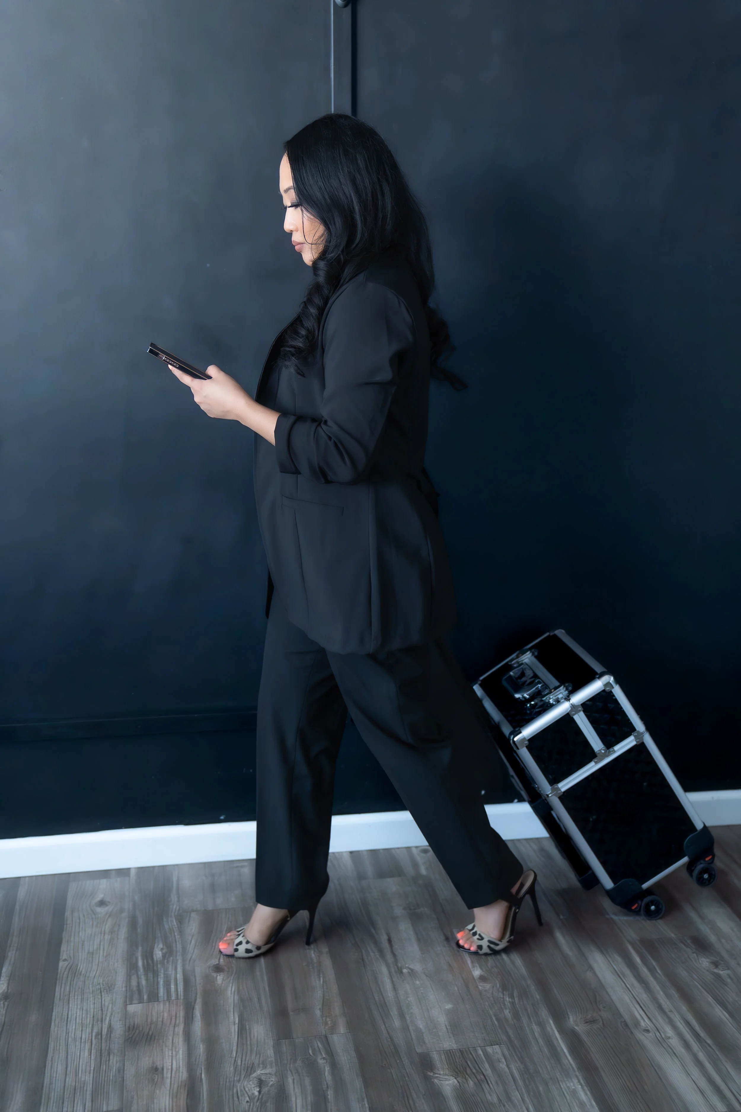 Girl wearing a black professional clothing and holding a roller bag