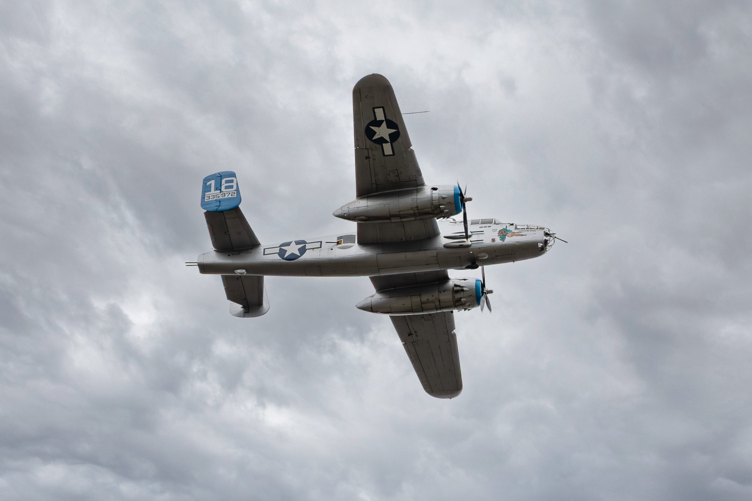 A vintage twin-engine military aircraft flying against a cloudy sky, marked with U.S. Air Force insignia.