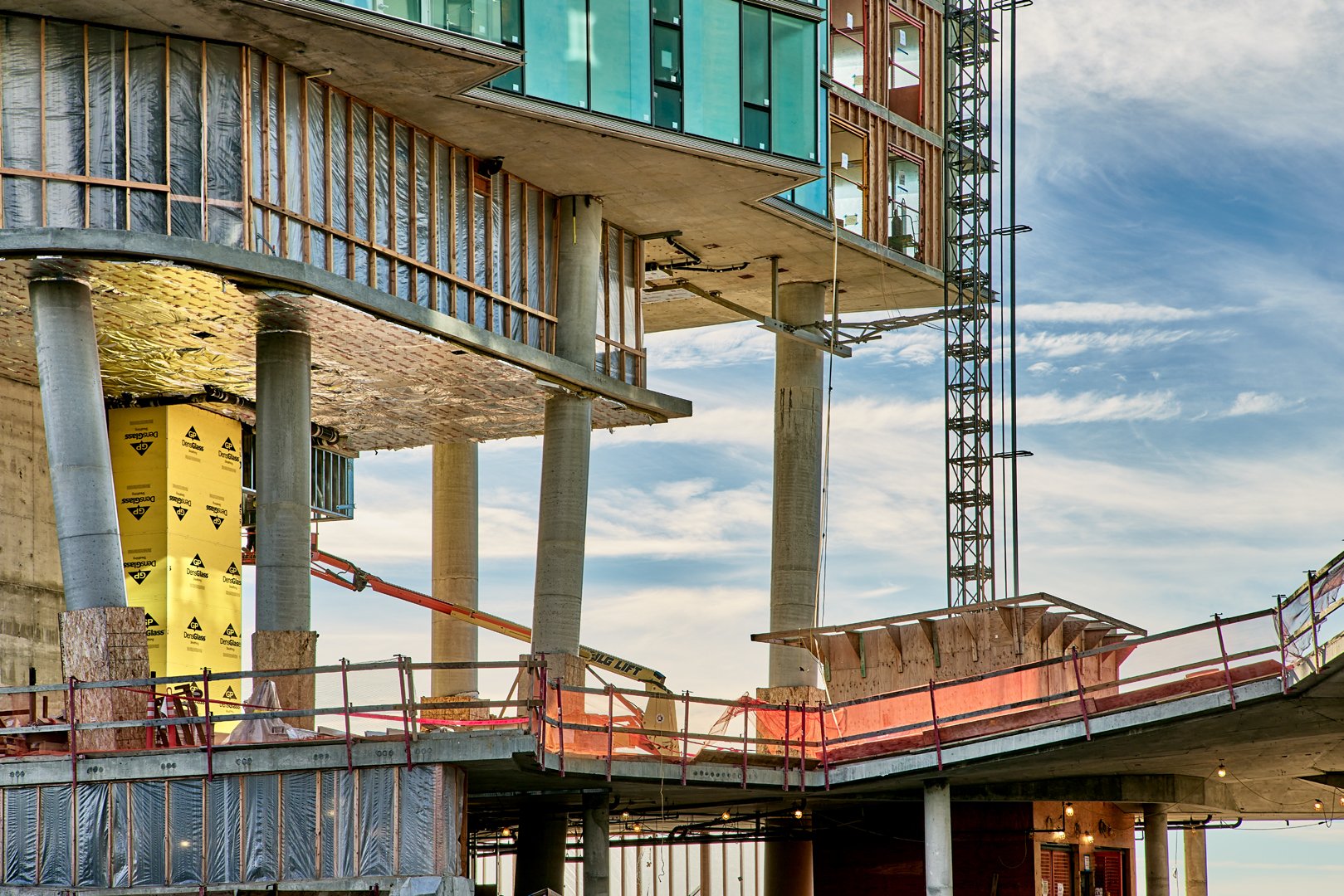 Under construction building with concrete pillars, glass windows, and scaffolding.