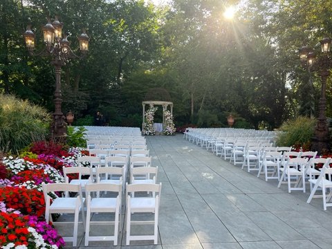 Outdoor wedding ceremony setup with white chairs and floral arch