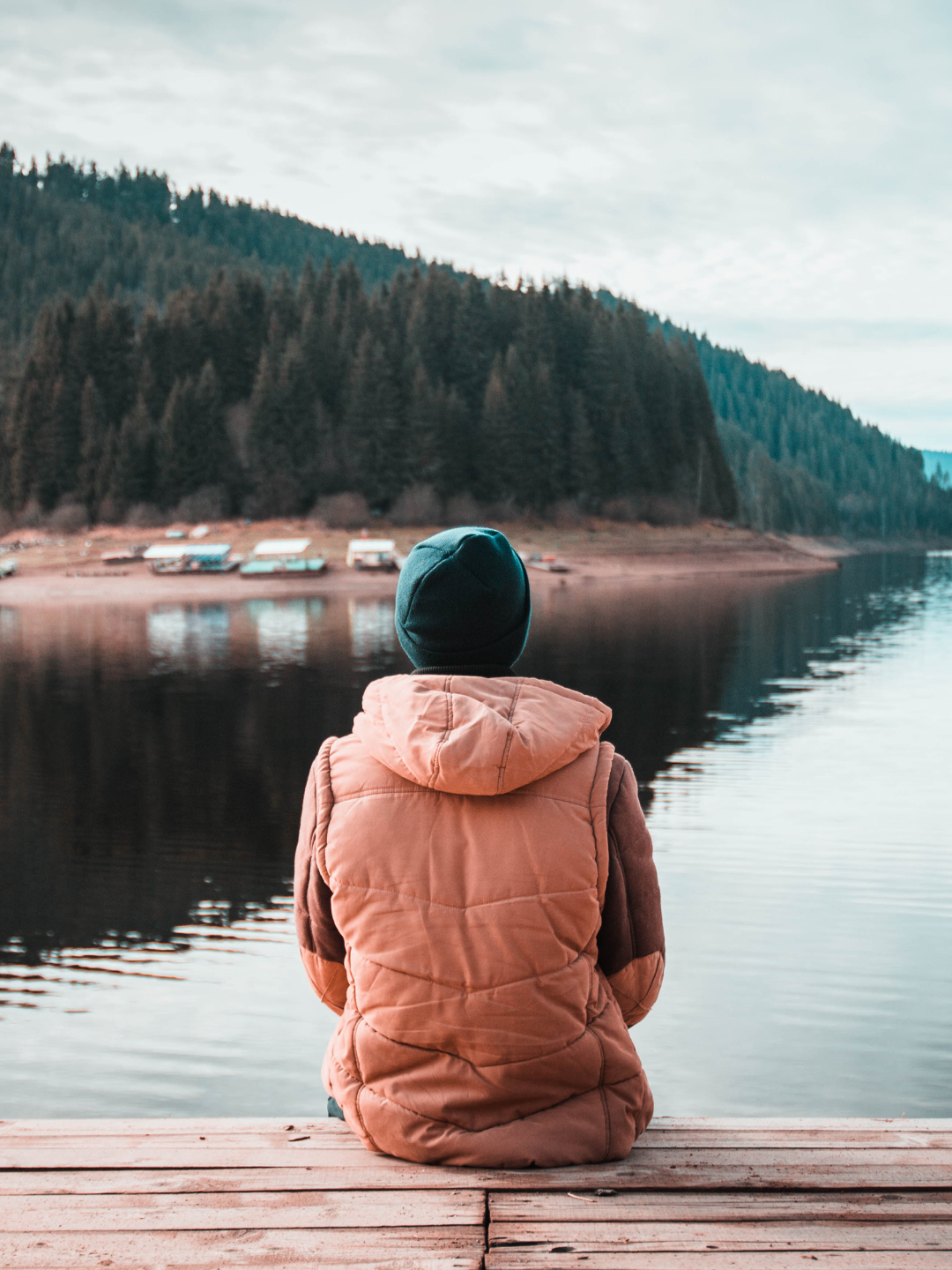person sitting at the end of a dock looking at water