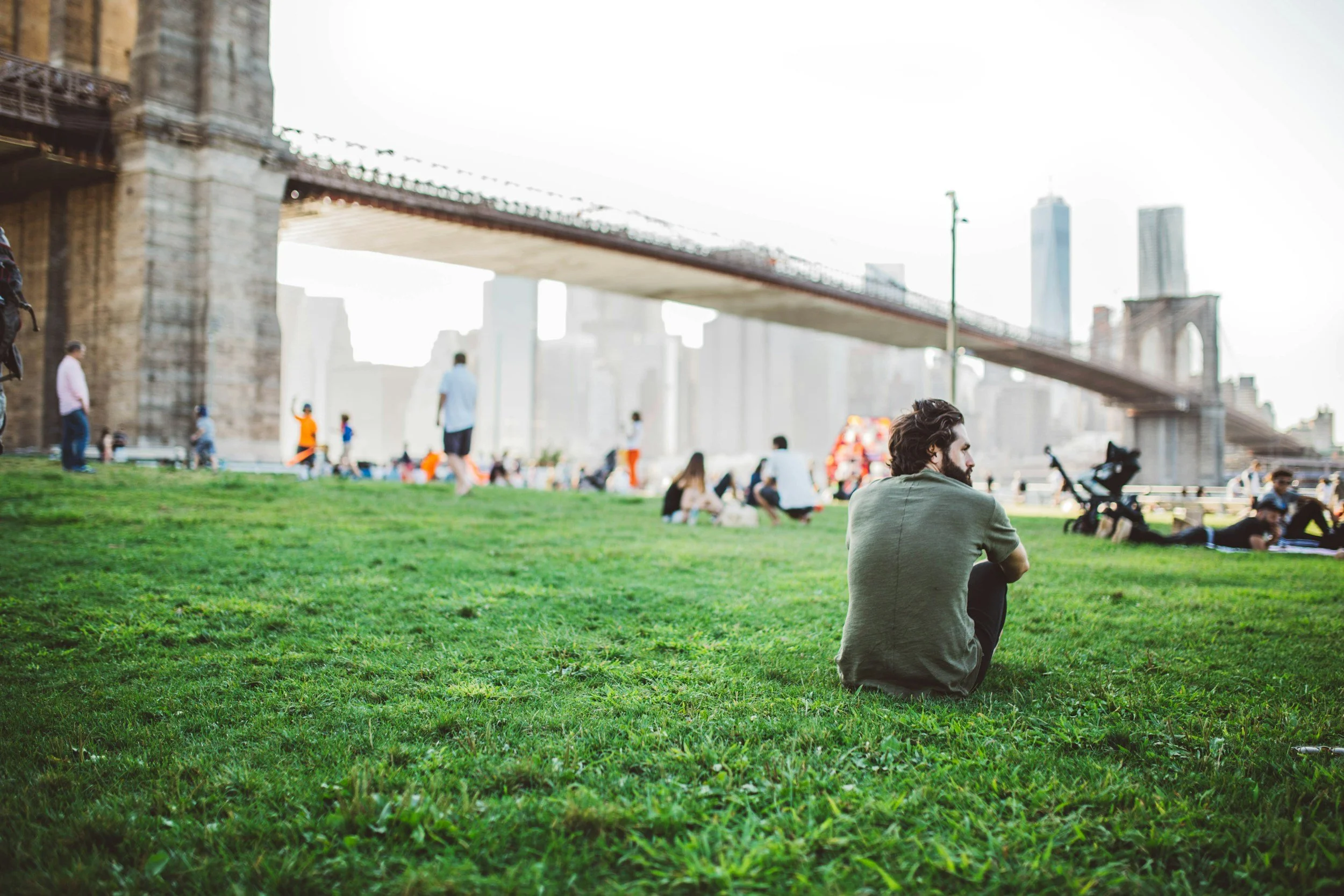 man sitting alone on a grassy hill surrounded by people