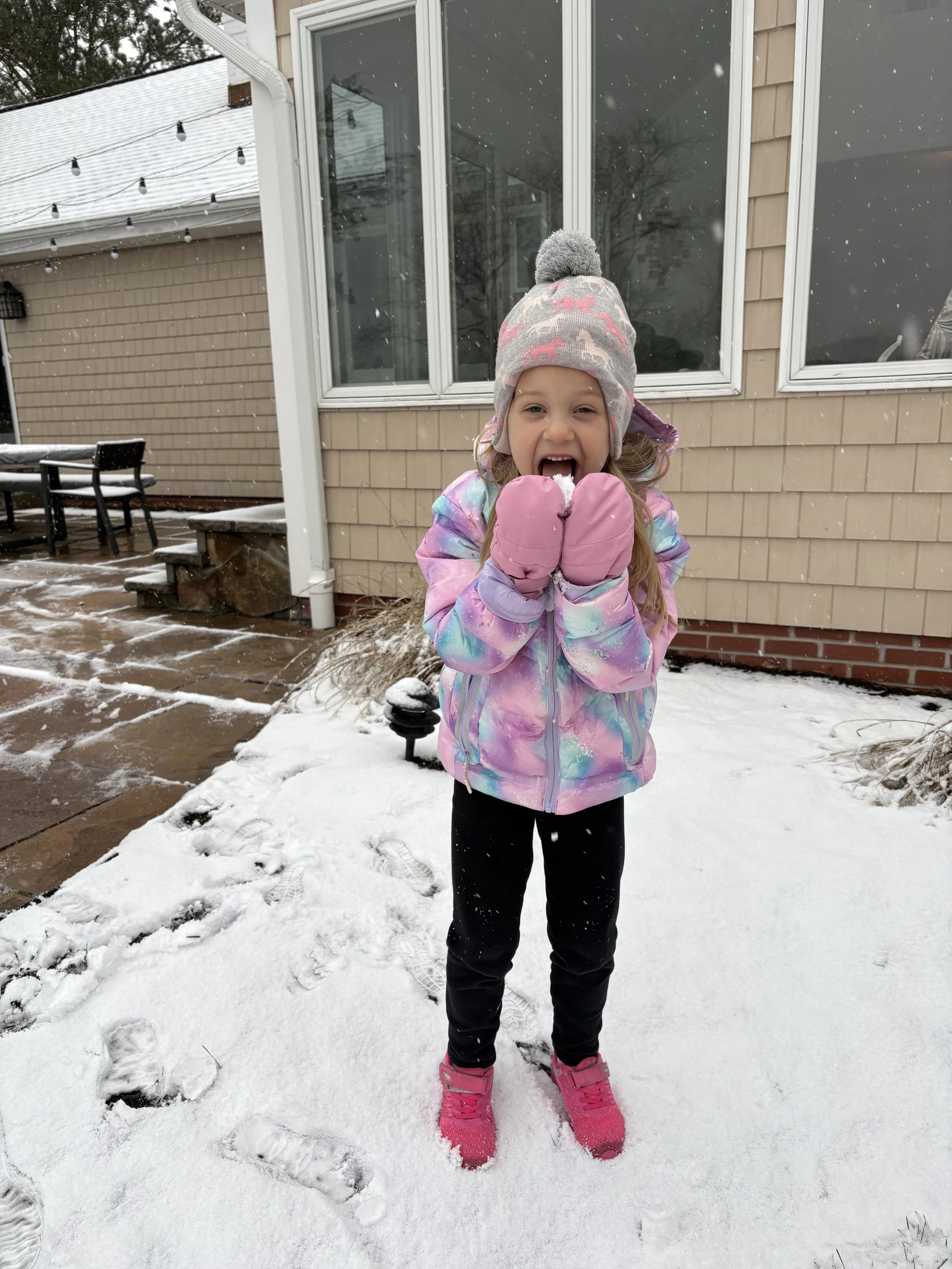 Little girl eating snow in the winter
