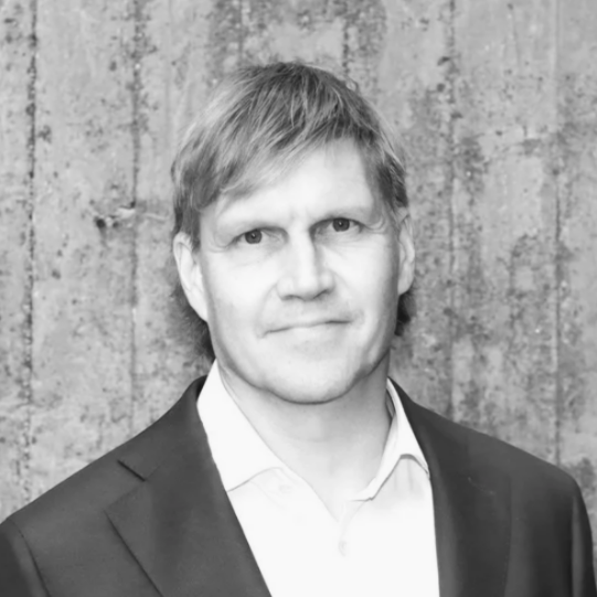 Black and white portrait photo of a person with light hair, smiling slightly, and facing the camera.