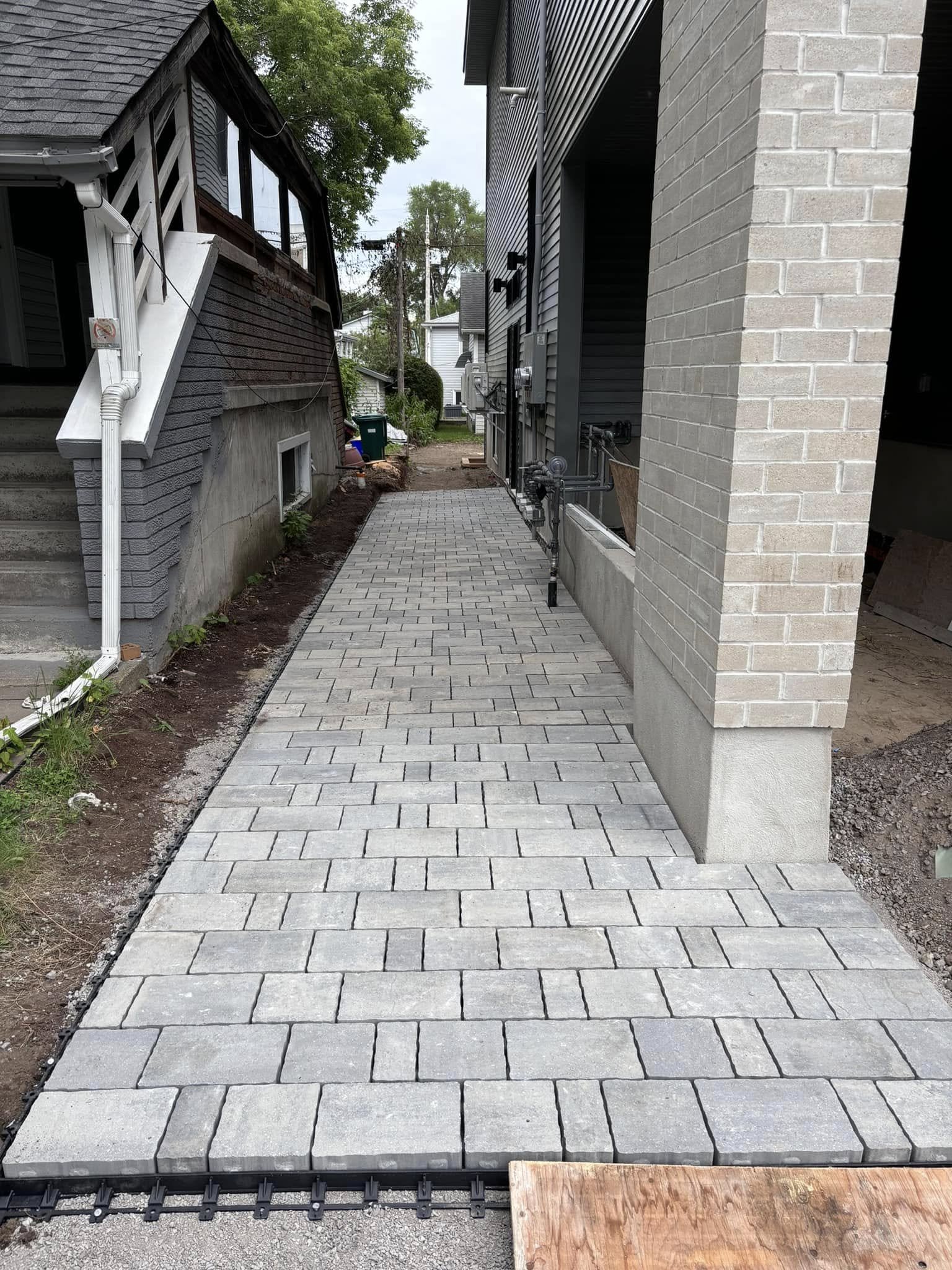 Paved walkway with gray rectangular bricks between two buildings.