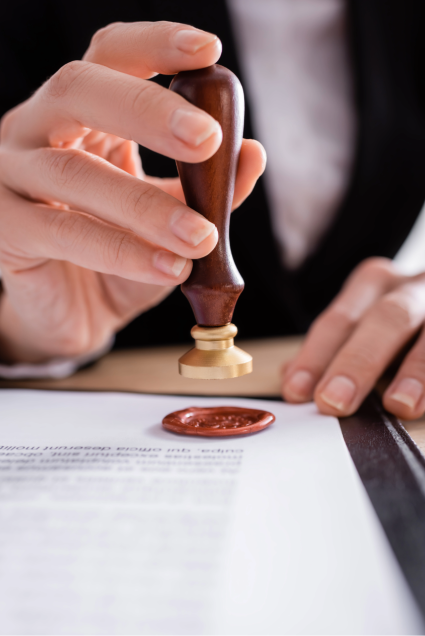 A person using a rubber stamp to sign a document with a wax seal.