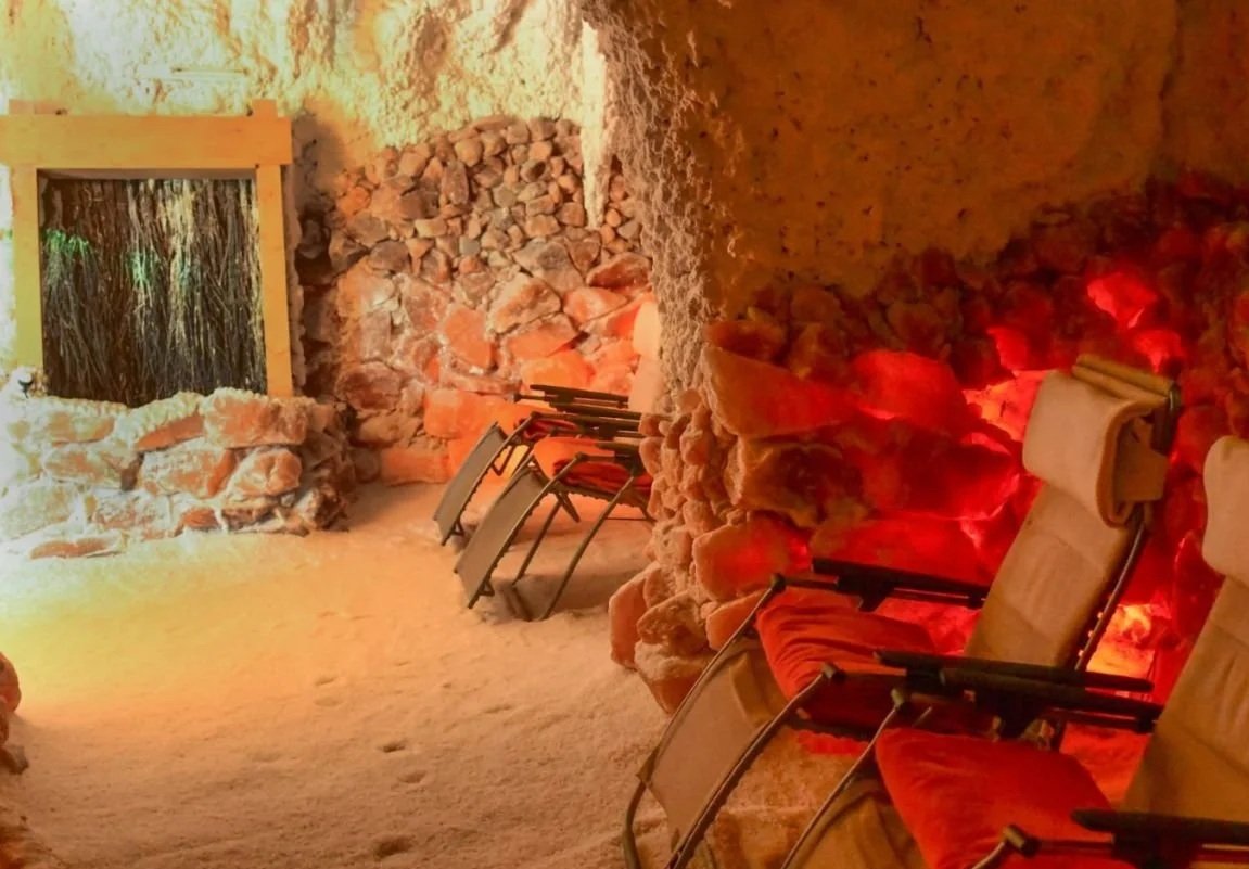 Ein Raum mit Liegen, die im Salz- oder Kupferschicht an der Wand stehen, und einem Fenster. Der Raum ist warm beleuchtet.