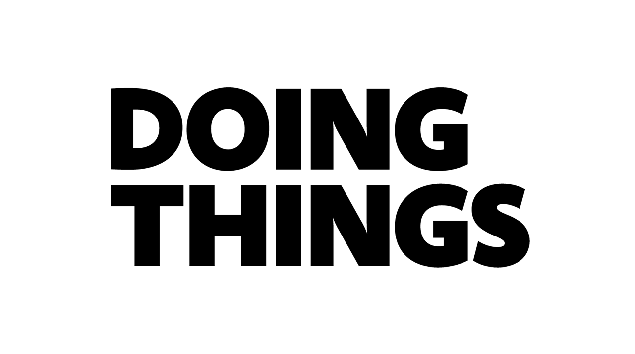 A solitary tree standing on the beach with waves crashing against the rocks, under an overcast sky.