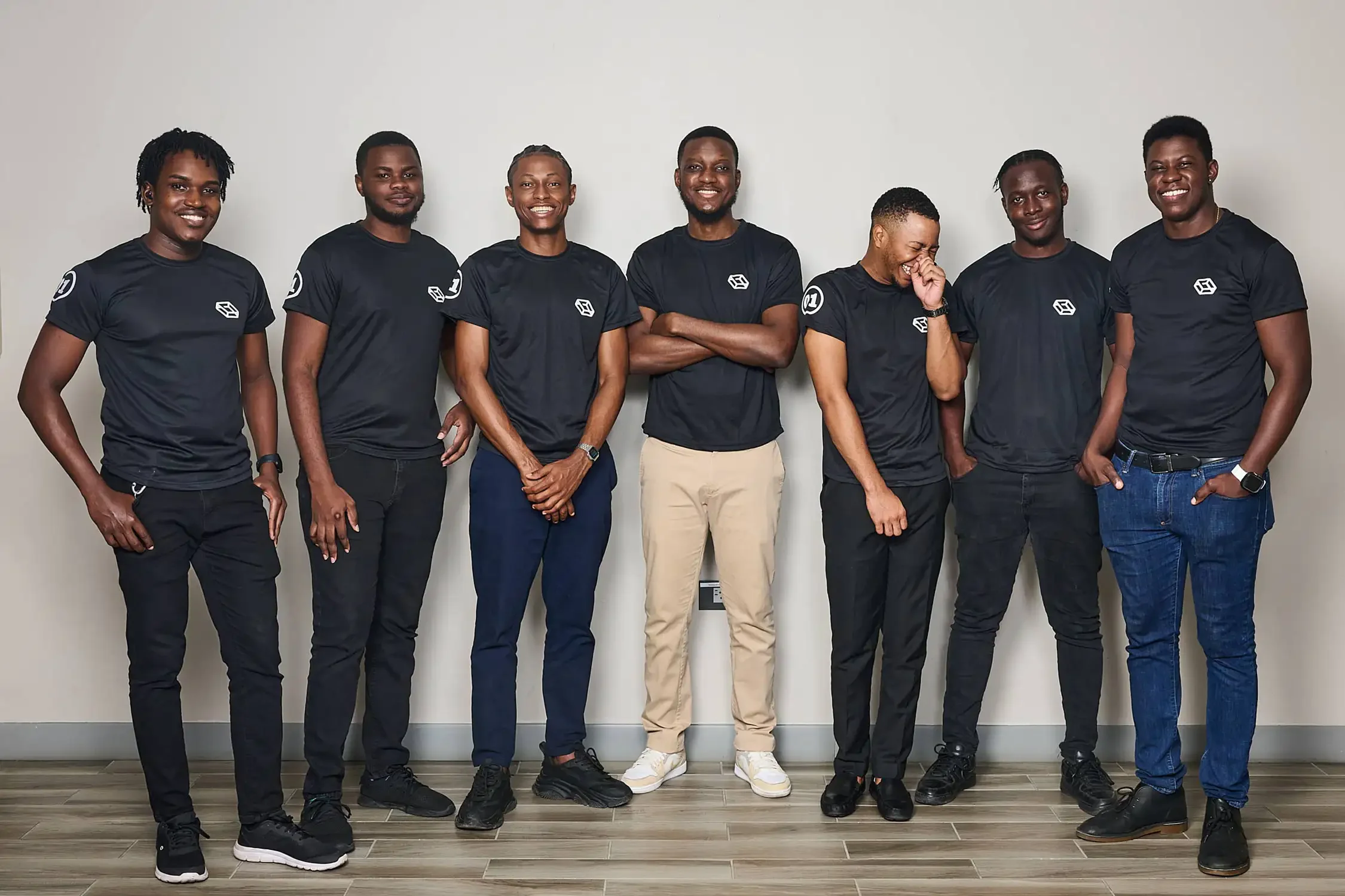 Corporate team group photo with seven men standing together beautiful lighting and setup reflecting friendship and confidence they are wearing matching black T-shirts.